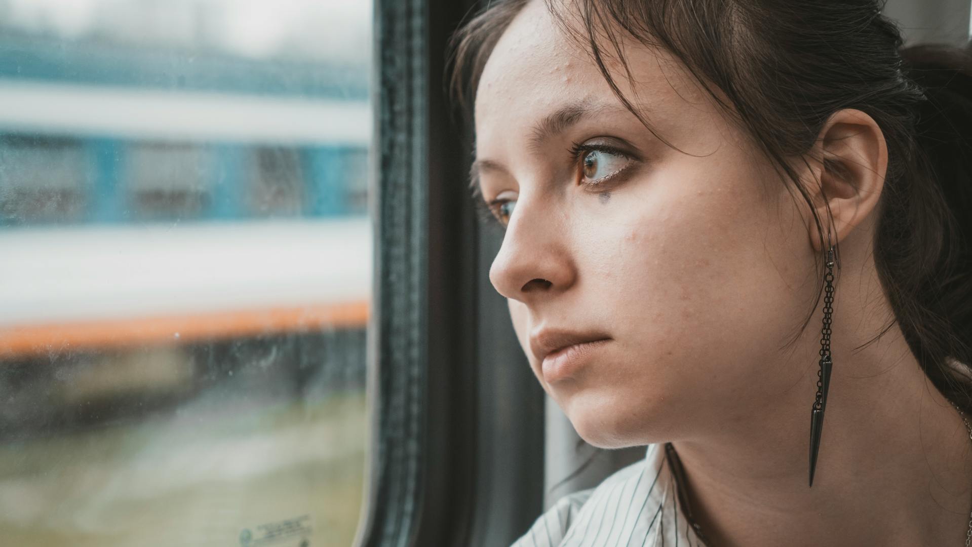 A woman staring worriedly out a window | Source: Pexels
