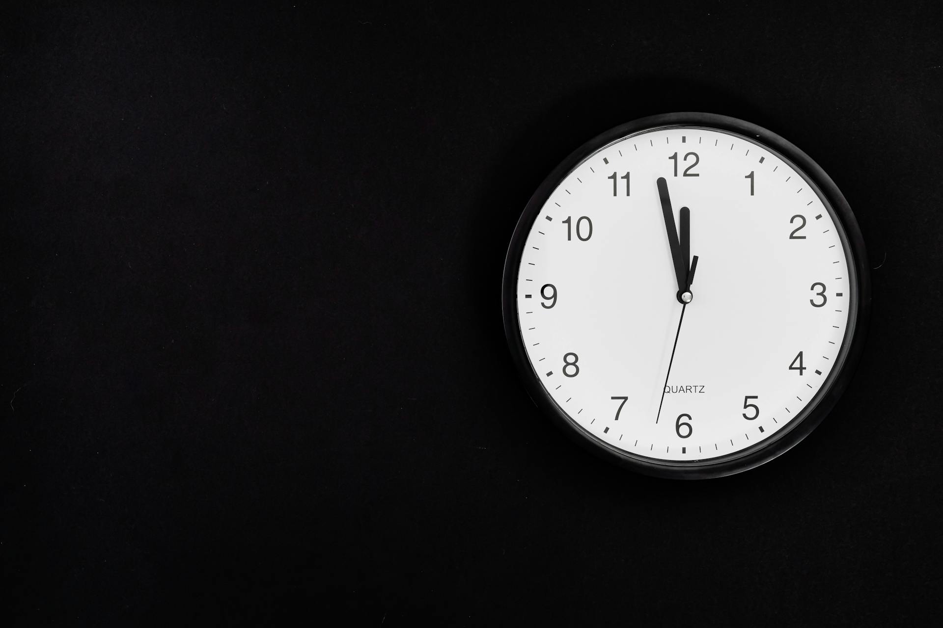 An old analog wall clock showing 11:58 p.m. | Source: Pexels