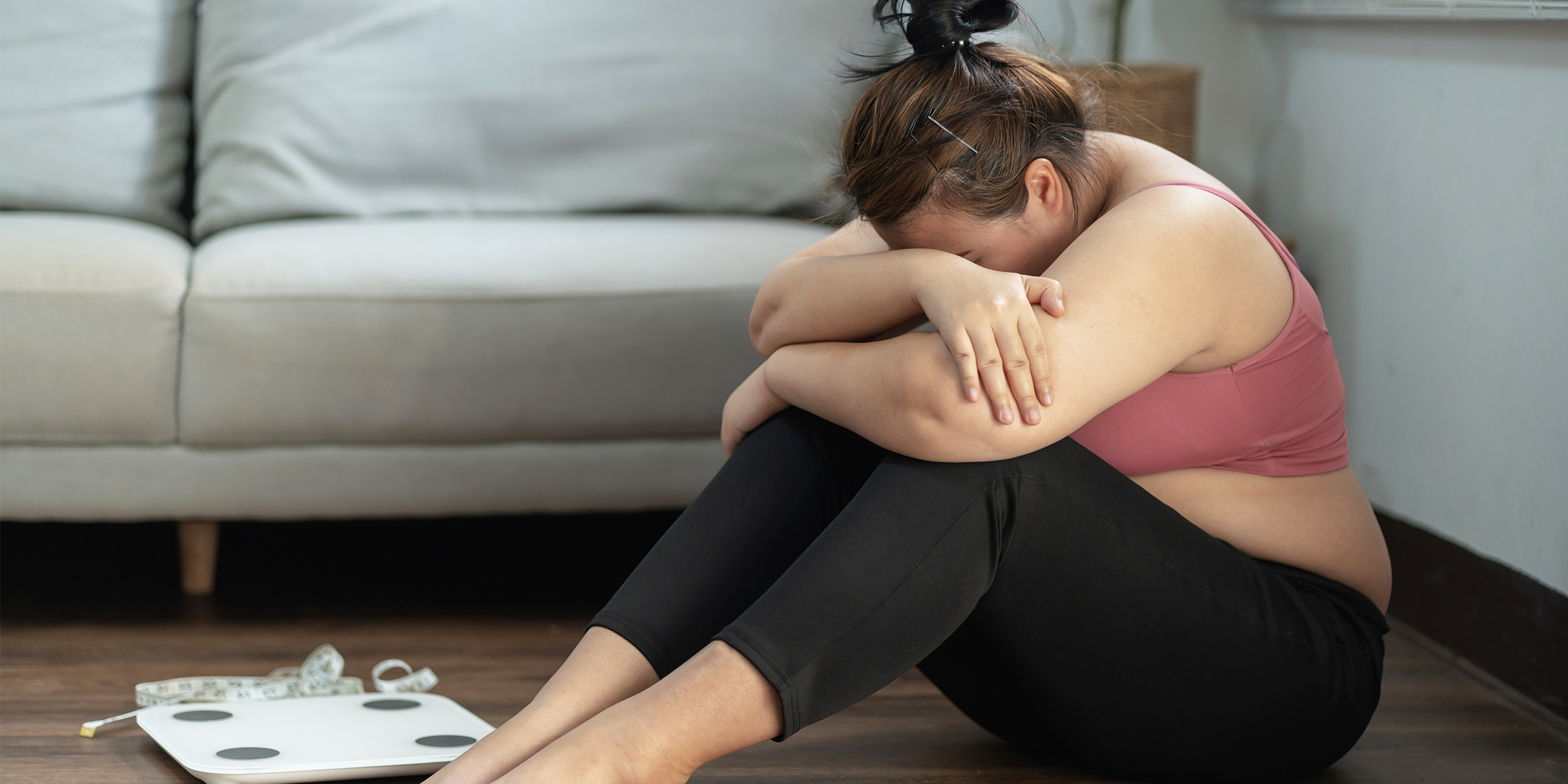 A crying woman sitting next to a weighing scale | Source: Shutterstock