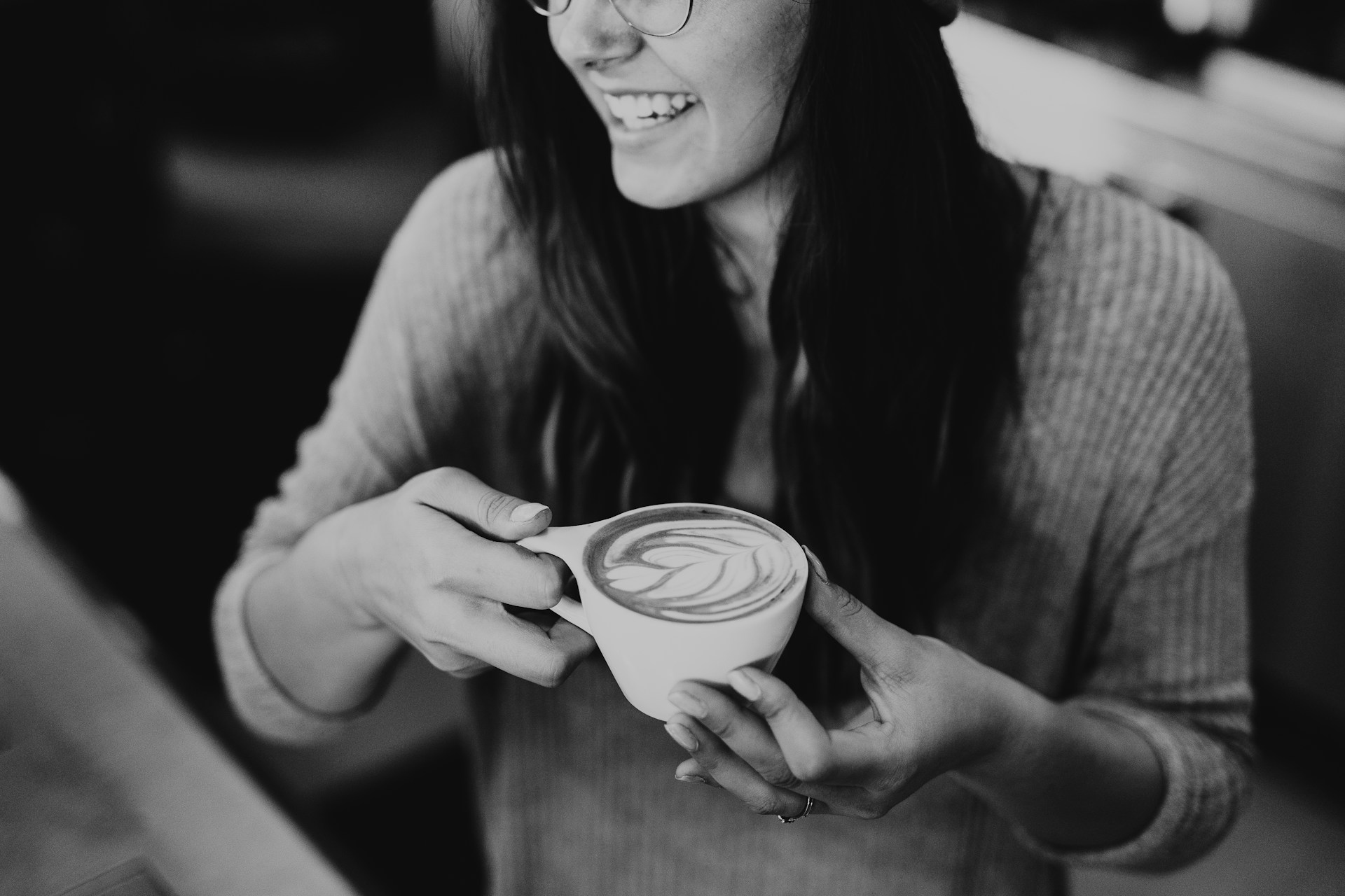 A woman laughing while holding a cup of coffee | Source: Unsplash