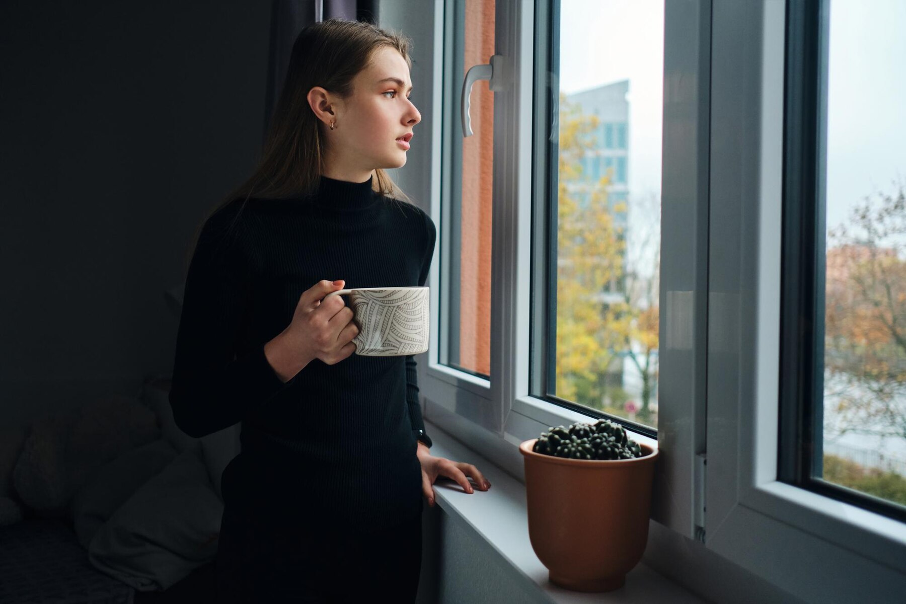 A concerned woman looking out of the window | Source: Freepik