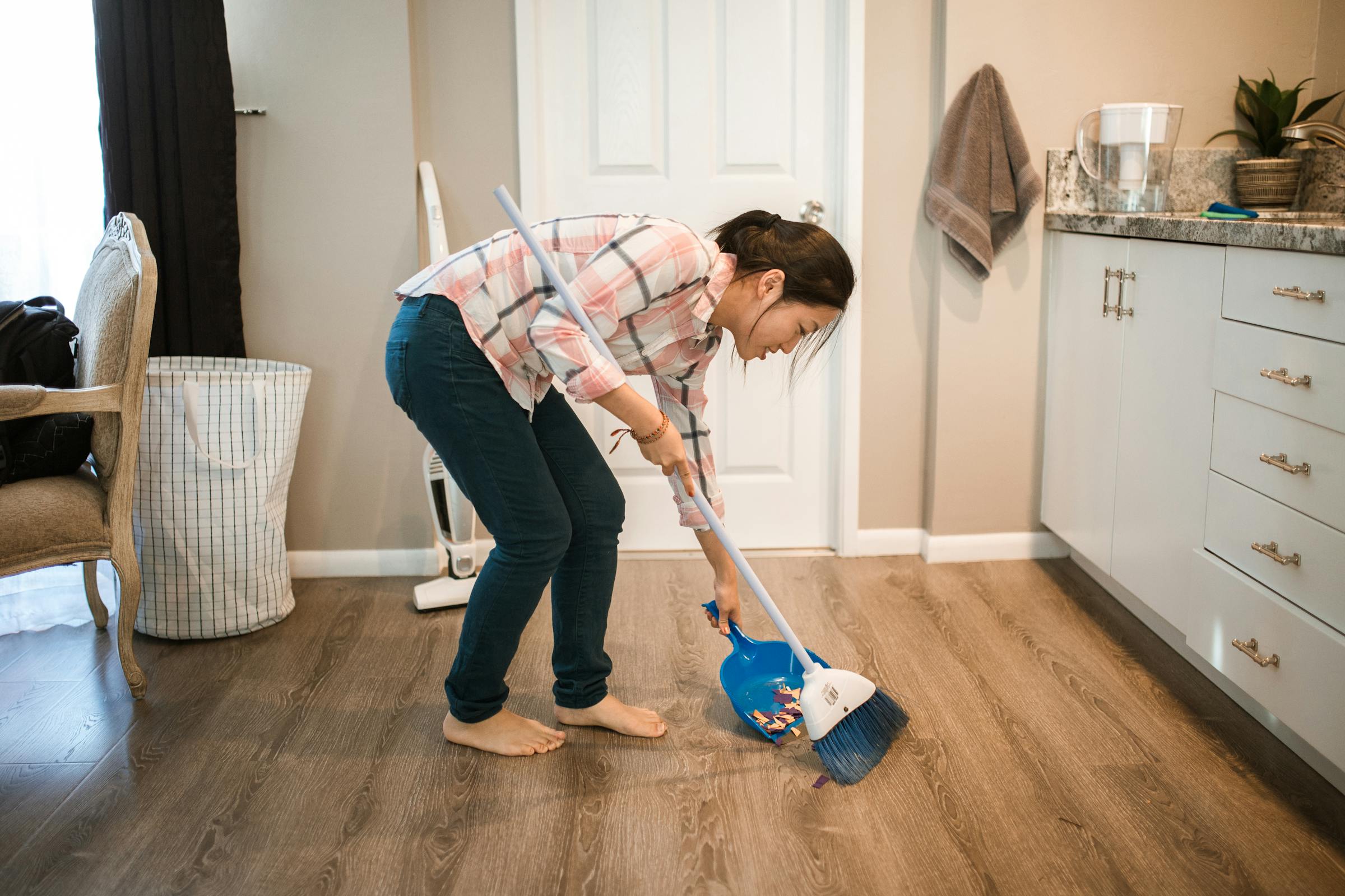 A woman sweeping while smiling | Source: Pexels