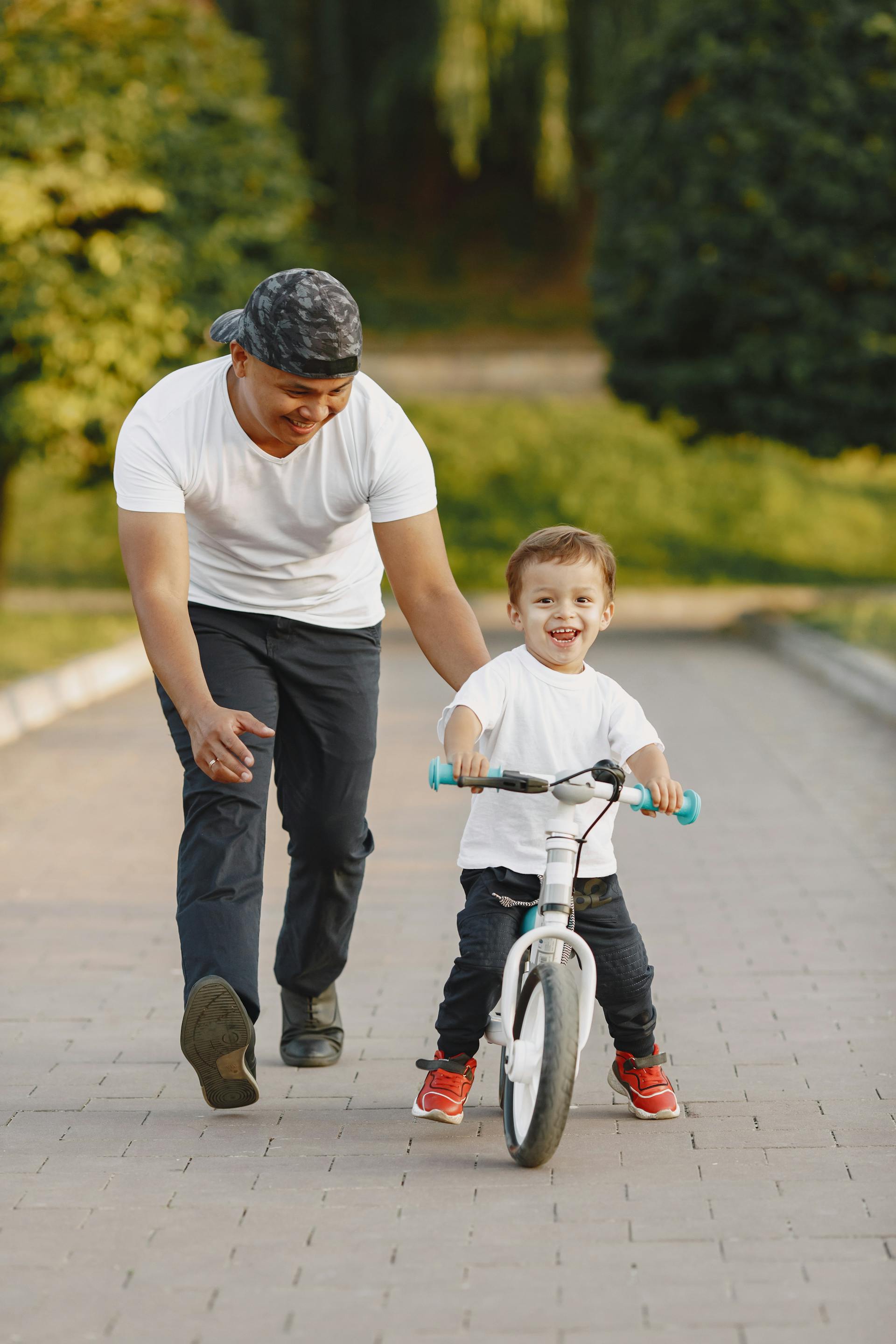 A man guiding his son to ride a bicycle | Source: Pexels