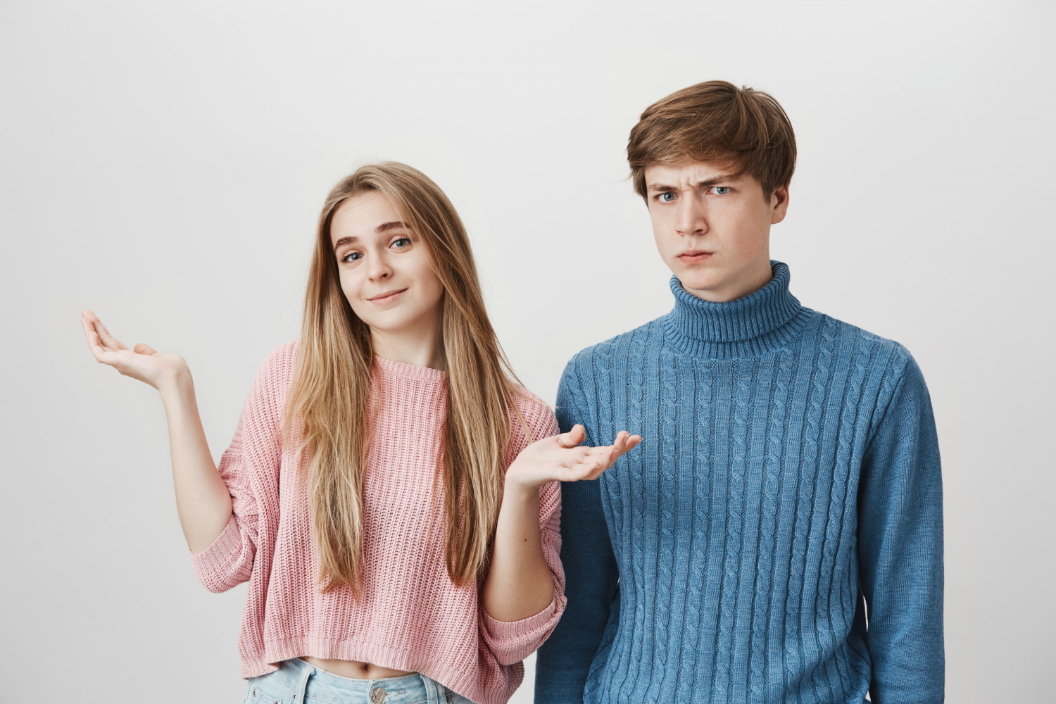 A young girl shrugging beside an annoyed teenage boy | Source: Freepik