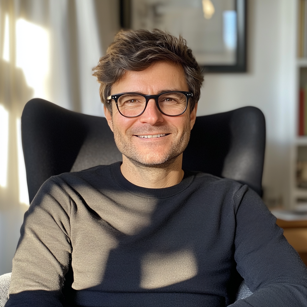 A smiling man wearing a black sweater and sitting in an armchair | Source: Midjourney