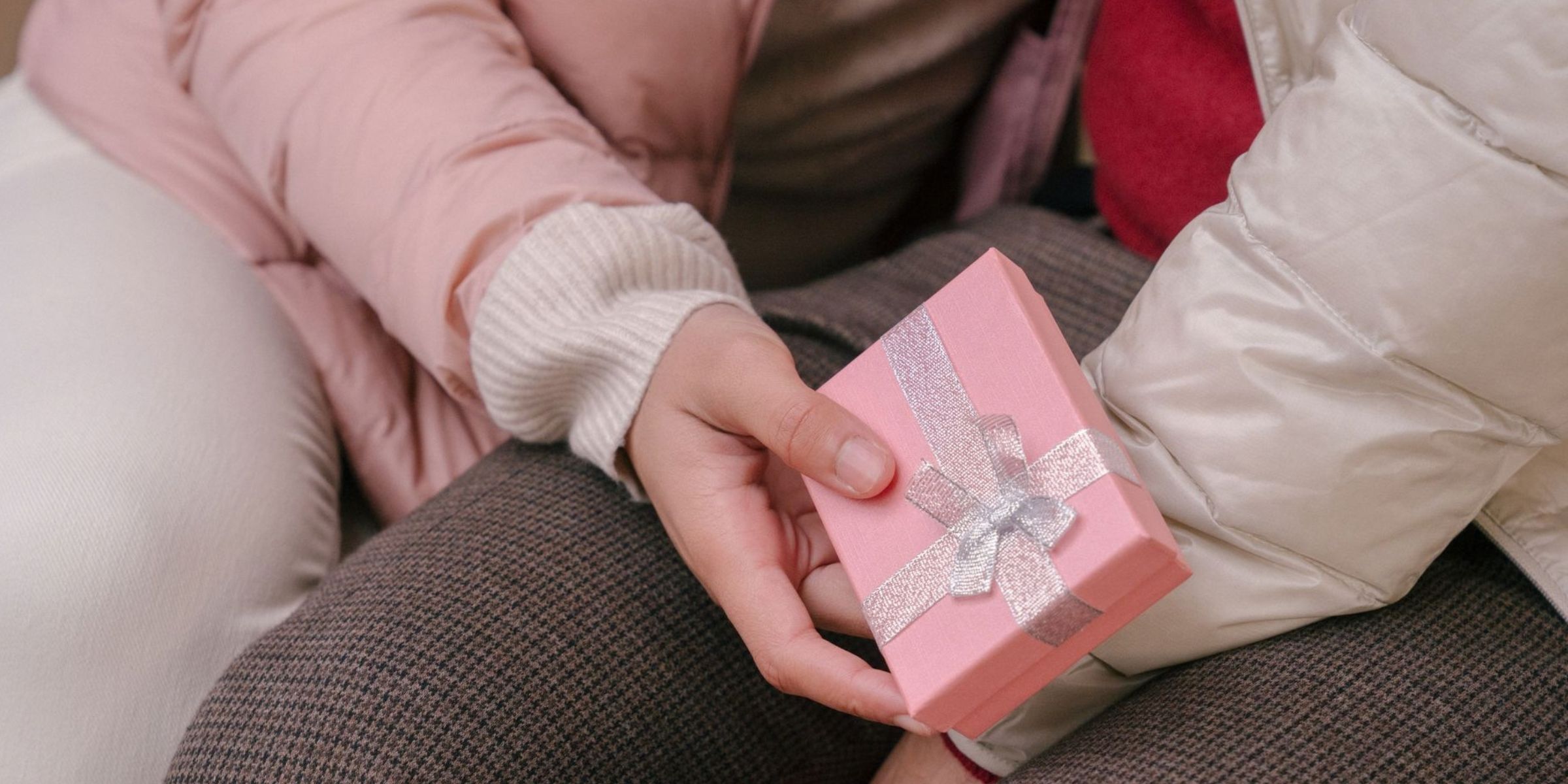 A close-up showing a person holding a pink gift box with a silver ribbon | Source: Pexels