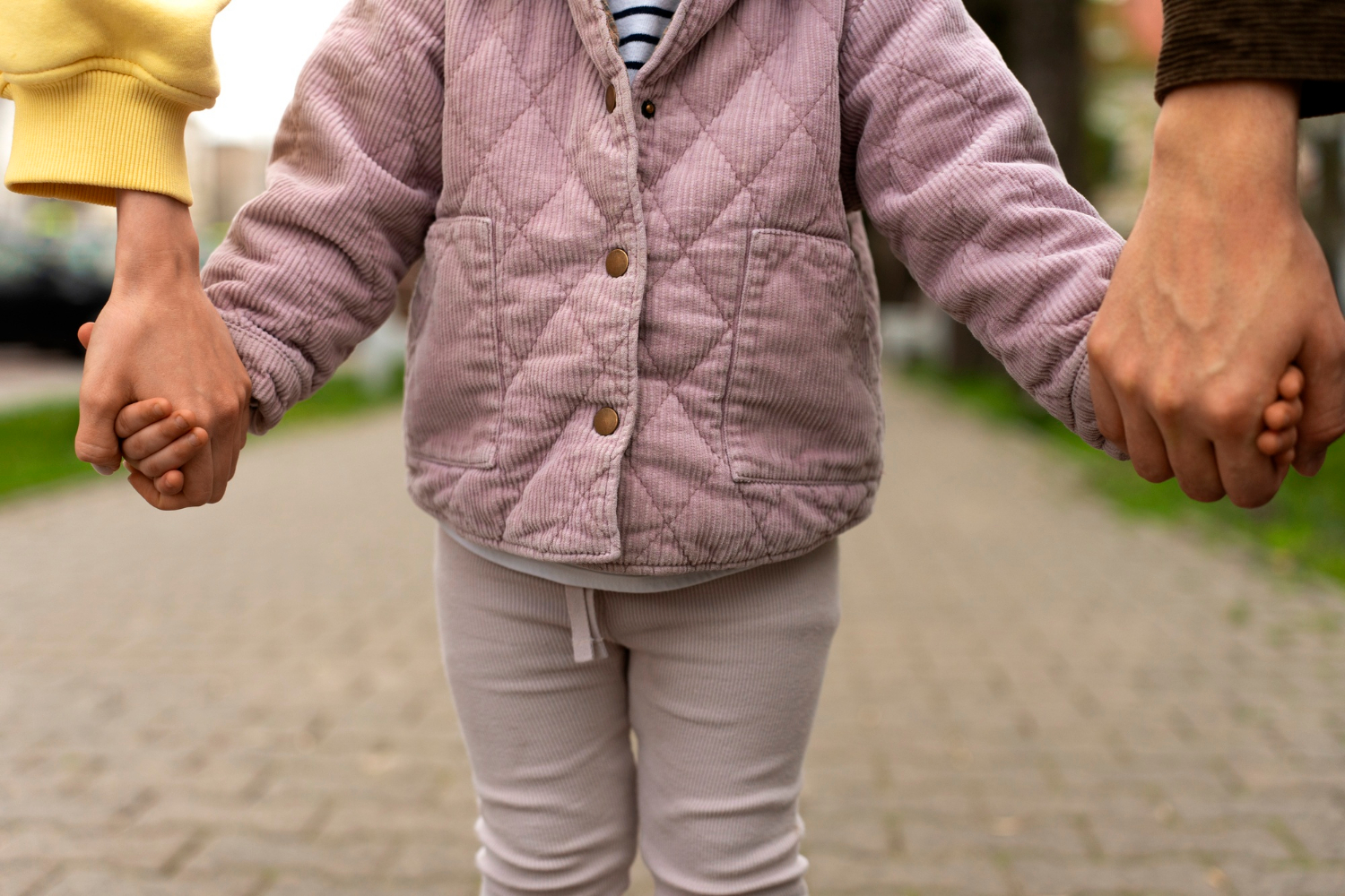 A child holding their parents' hands | Source: Freepik