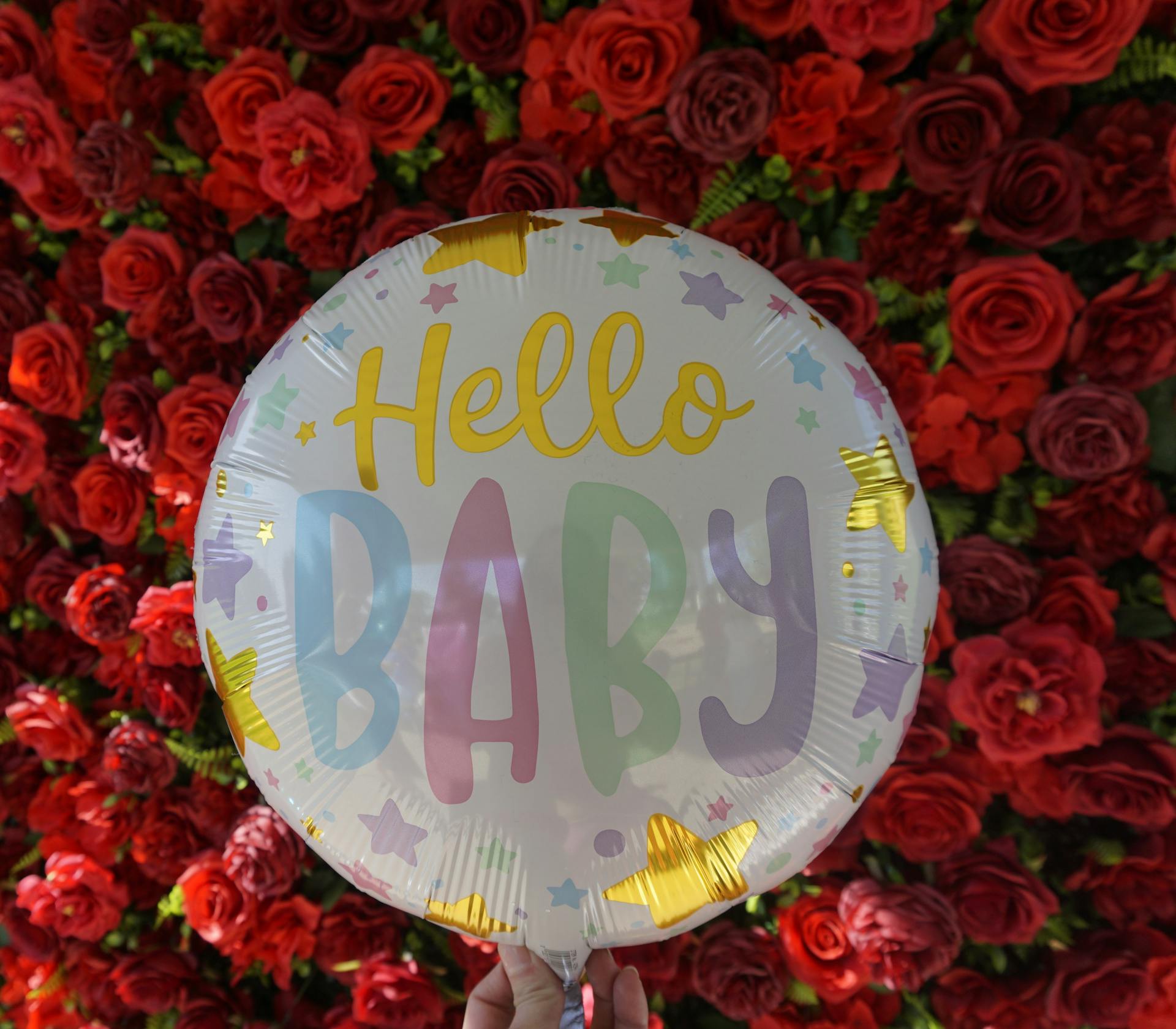 A person holding a balloon with red roses in the background | Source: Pexels