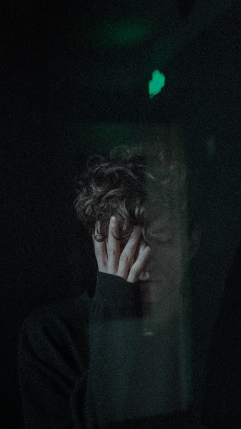 A young man covering his face with his hand | Source: Pexels