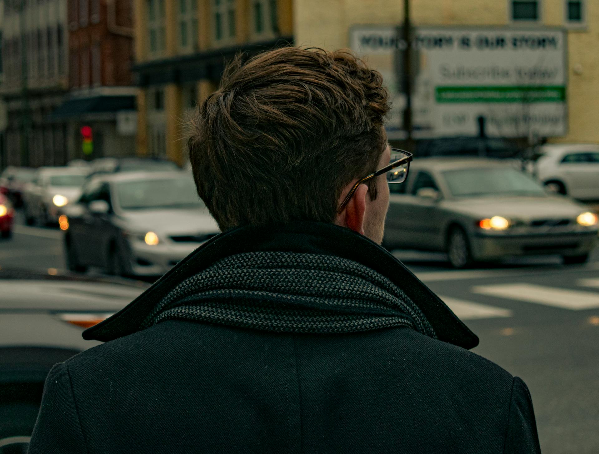 A back-view of a man in a black jacket standing on the road | Source: Pexels