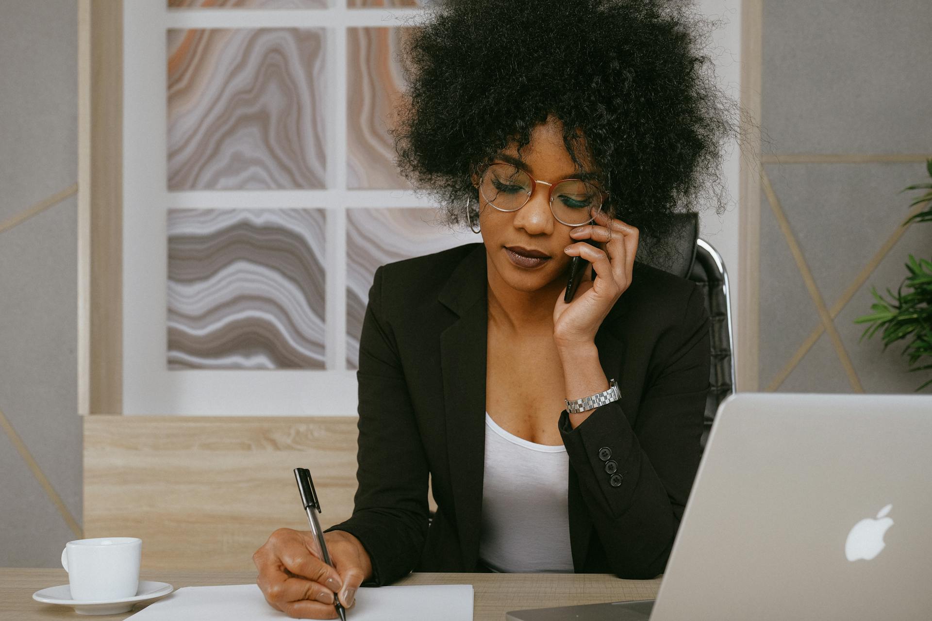 A woman talking on the phone in her office | Source: Pexels