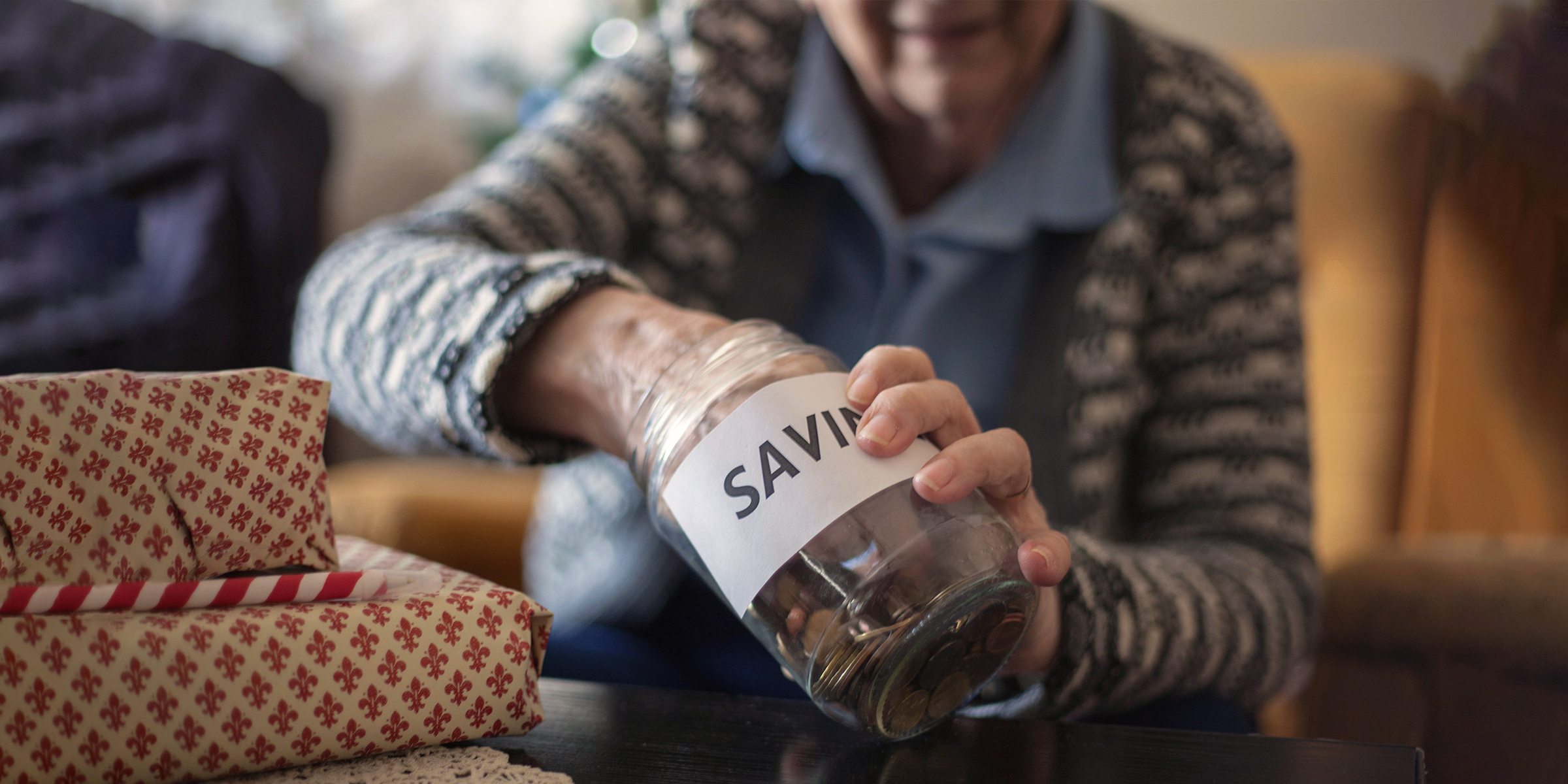 Elderly woman dipping her hand into her jar of savings | Source: Shutterstock