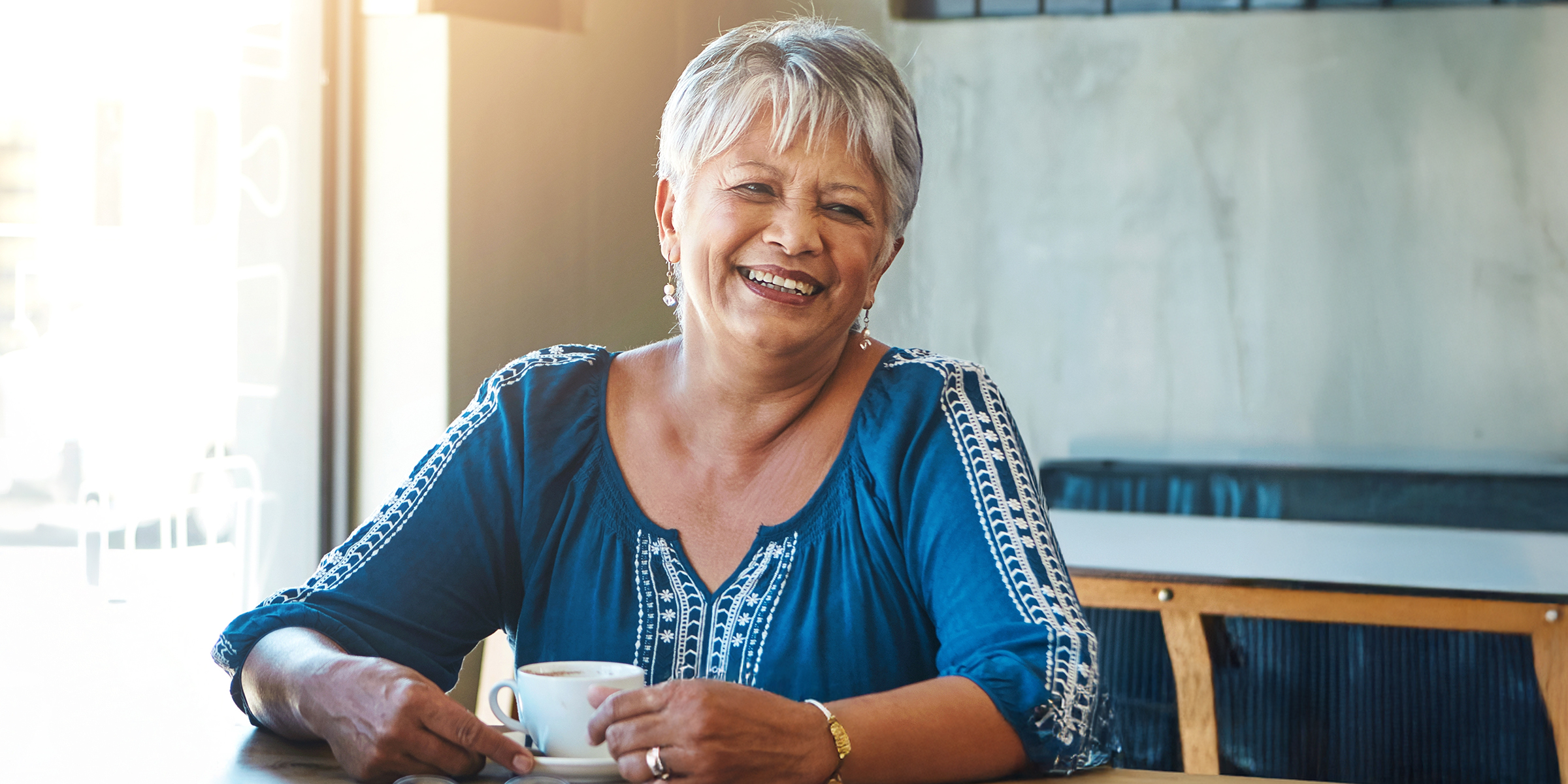 A delighted older woman with short gray hair sitting at a table | Source: Shutterstock