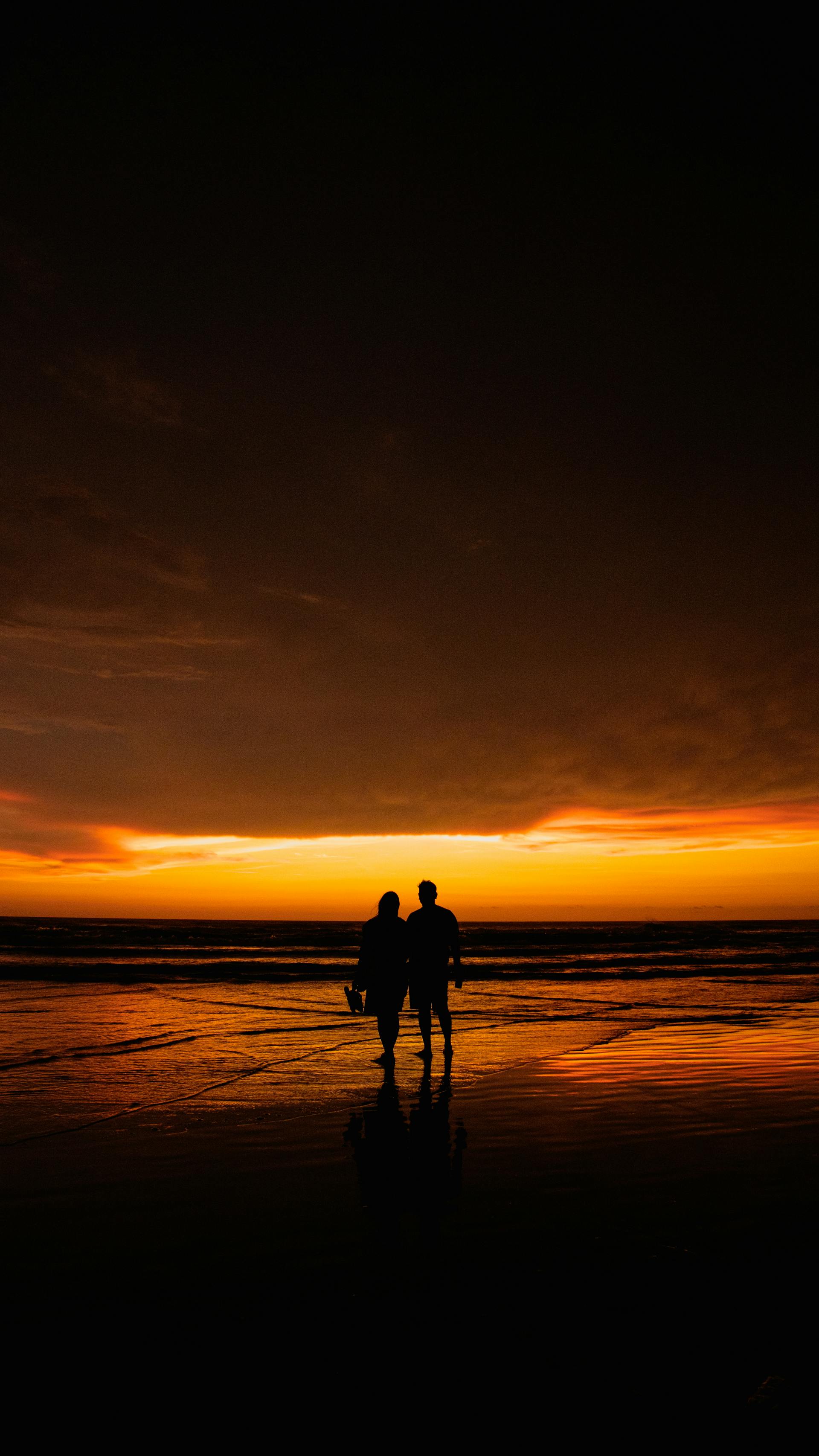 A silhouette of a couple walking on the beach during sunset | Source: Pexels