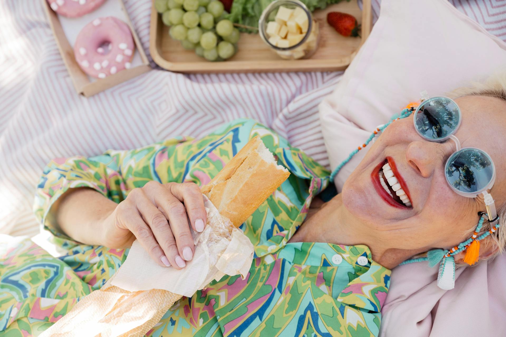 A senior woman lying down while holding a burger | Source: Pexels
