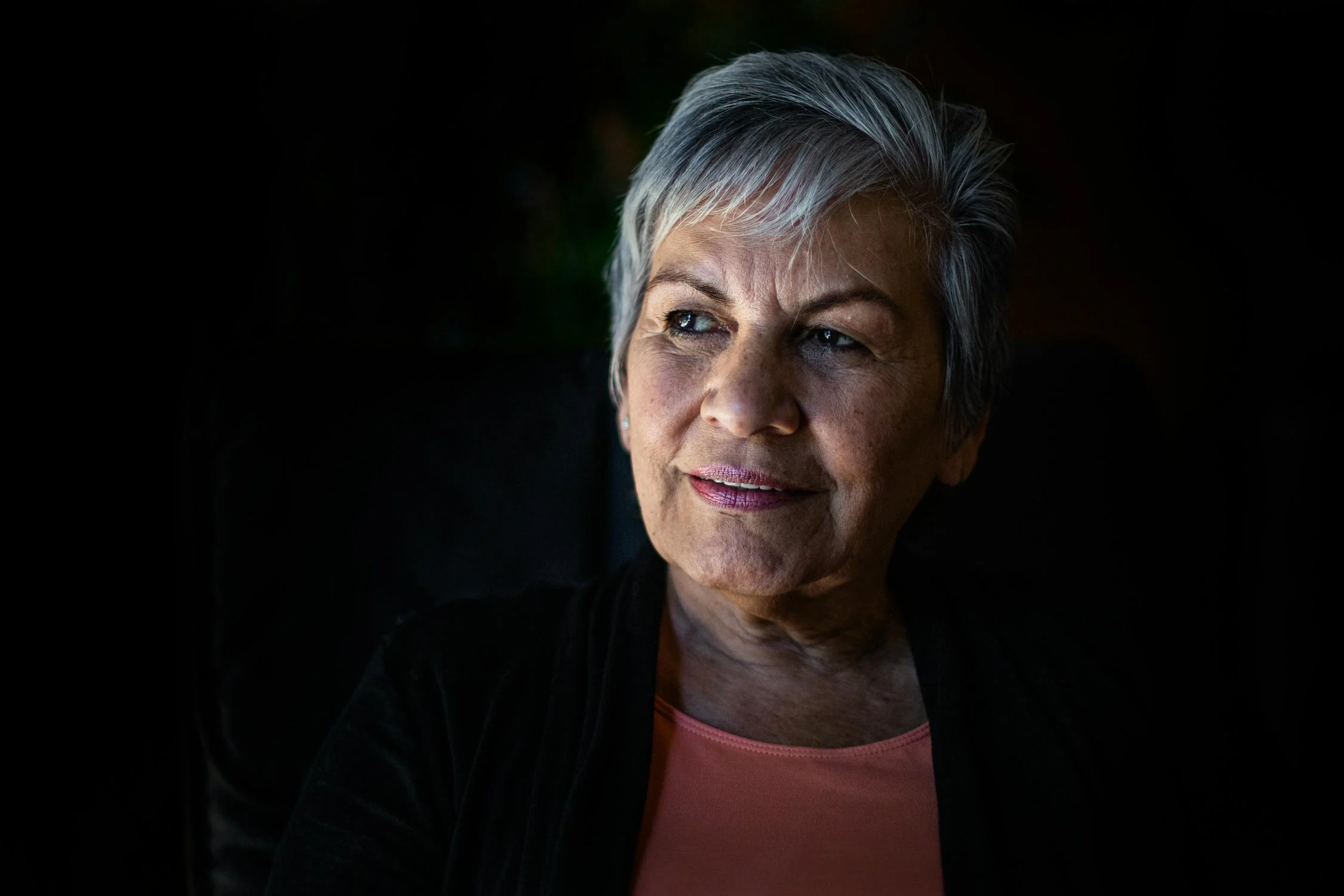 Una mujer sonriente mirando a su lado ⏐ Fuente: Pexels