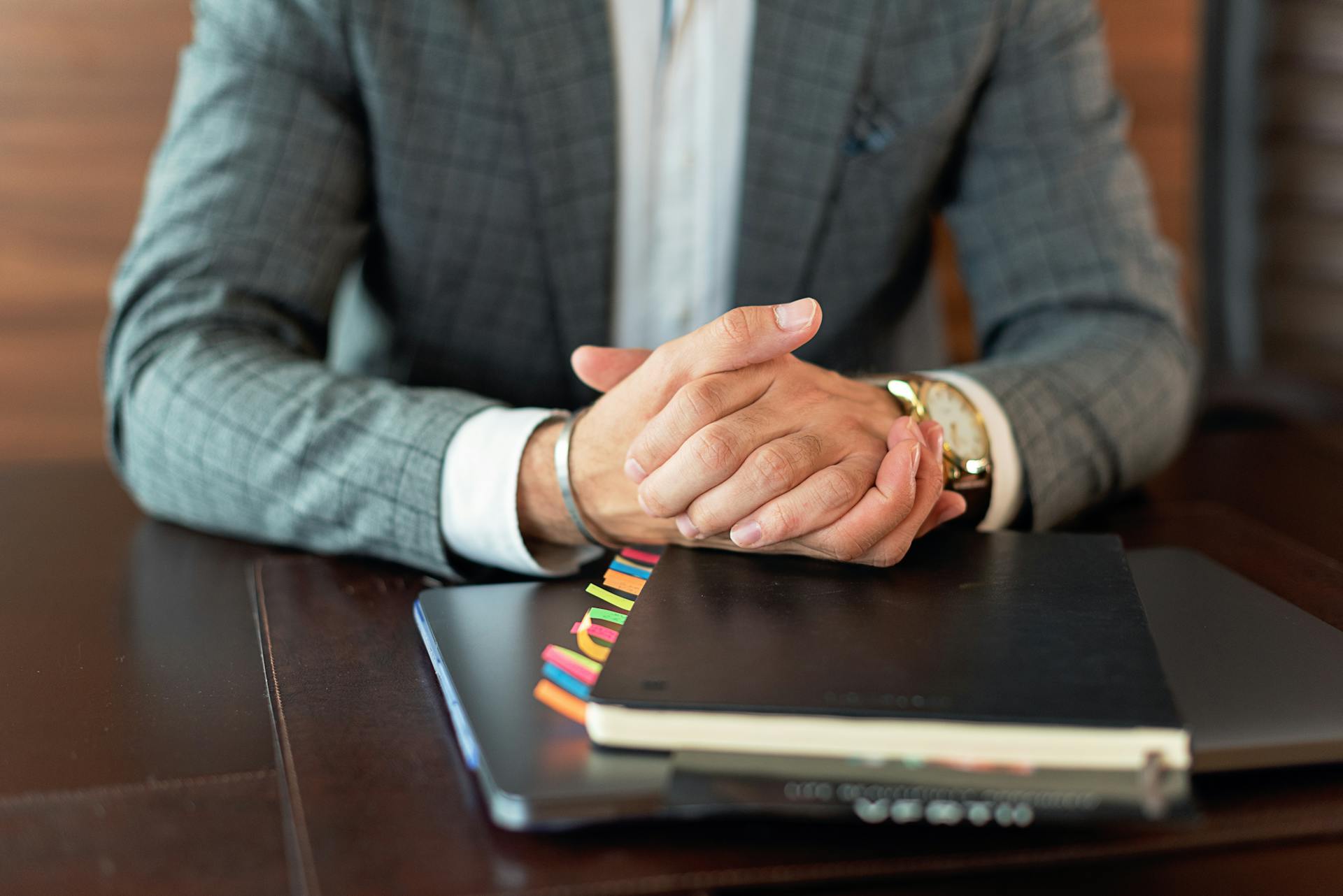 A close-up of a man's clasped hands as he sits in his office | Source: Pexels