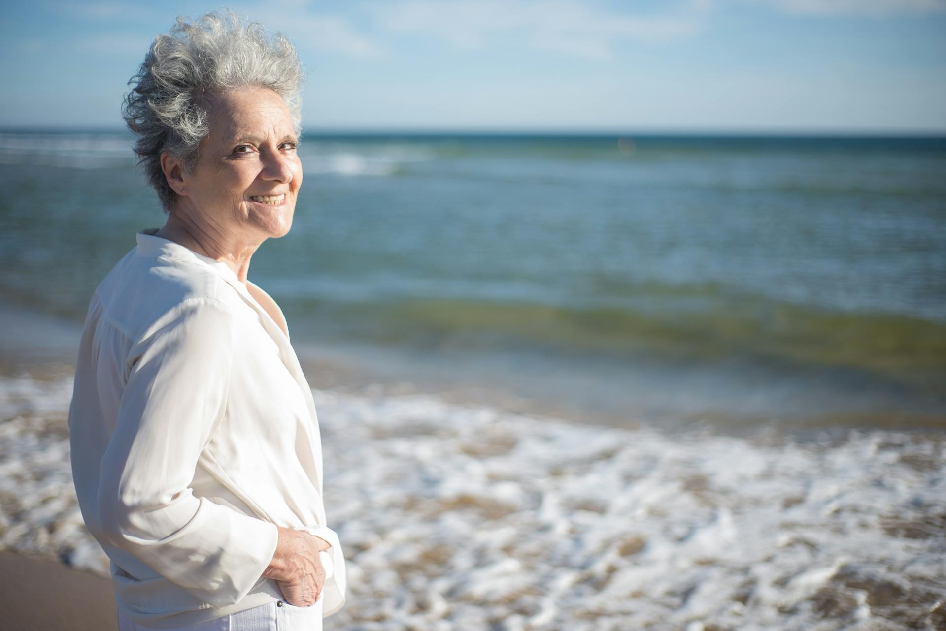 A senior woman smiling while standing at the shore | Source: Pexels