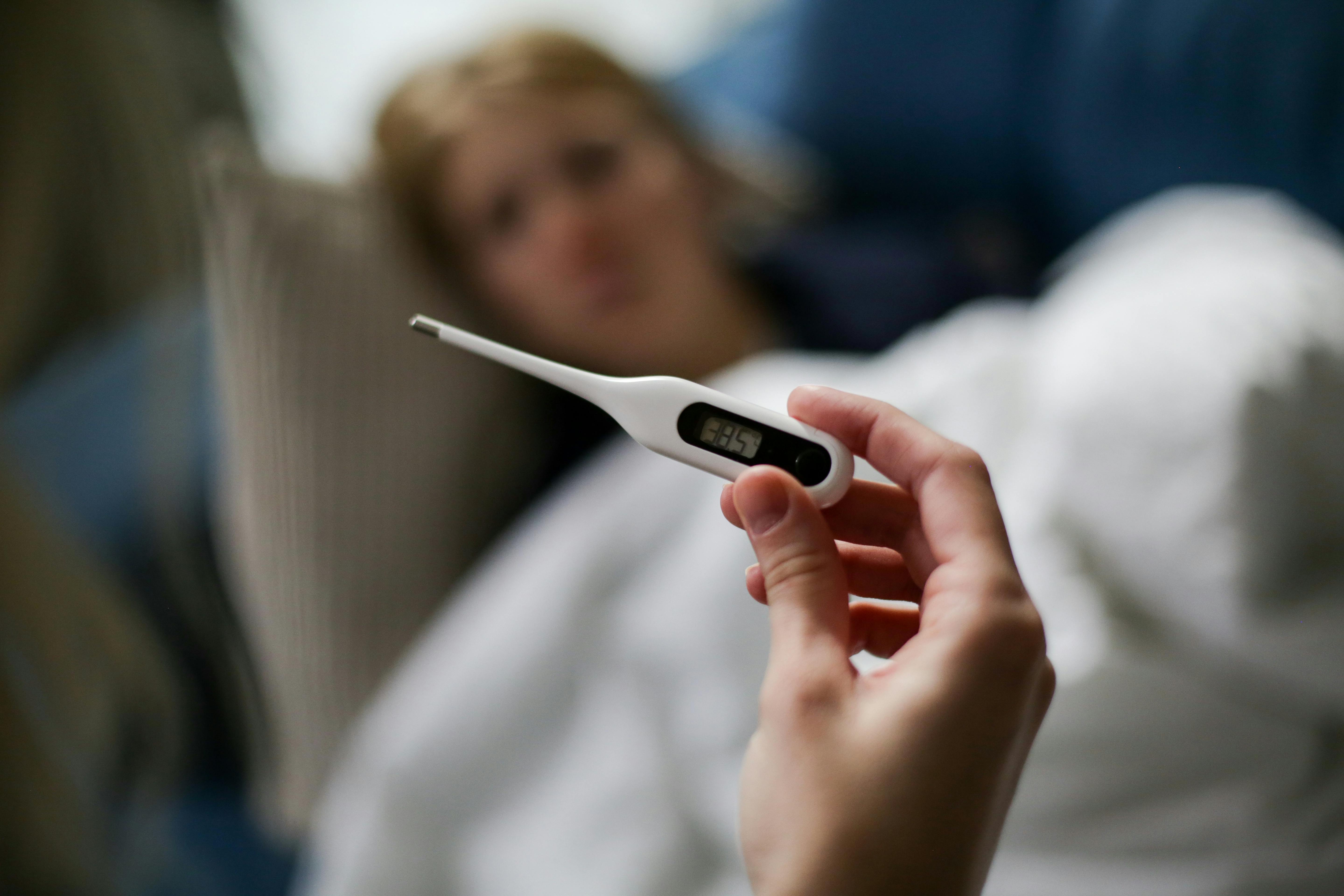 A sick woman in bed getting her temperature taken | Source: Pexels