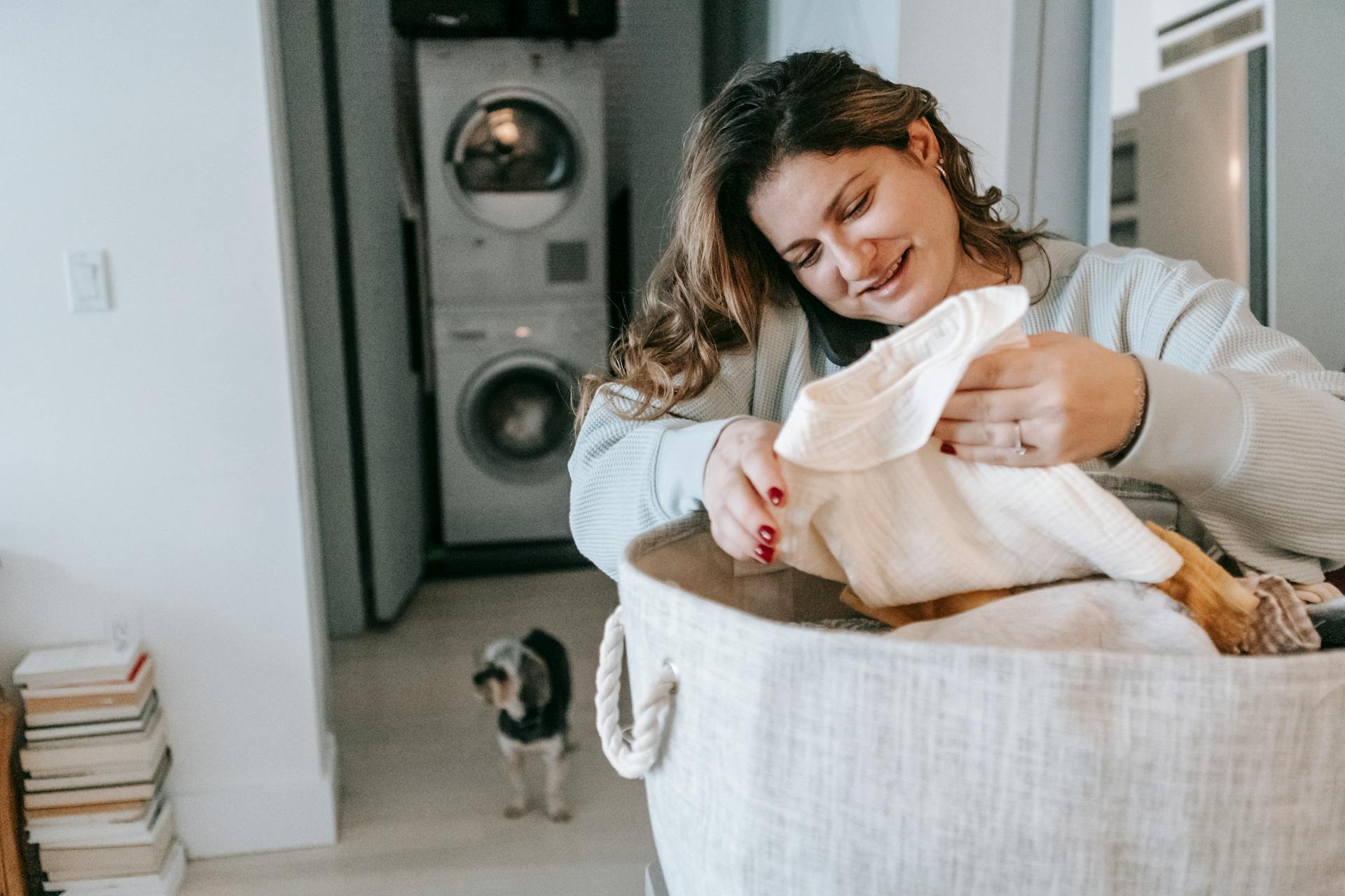 A woman smiling hopefully while folding clothes | Source: Pexels
