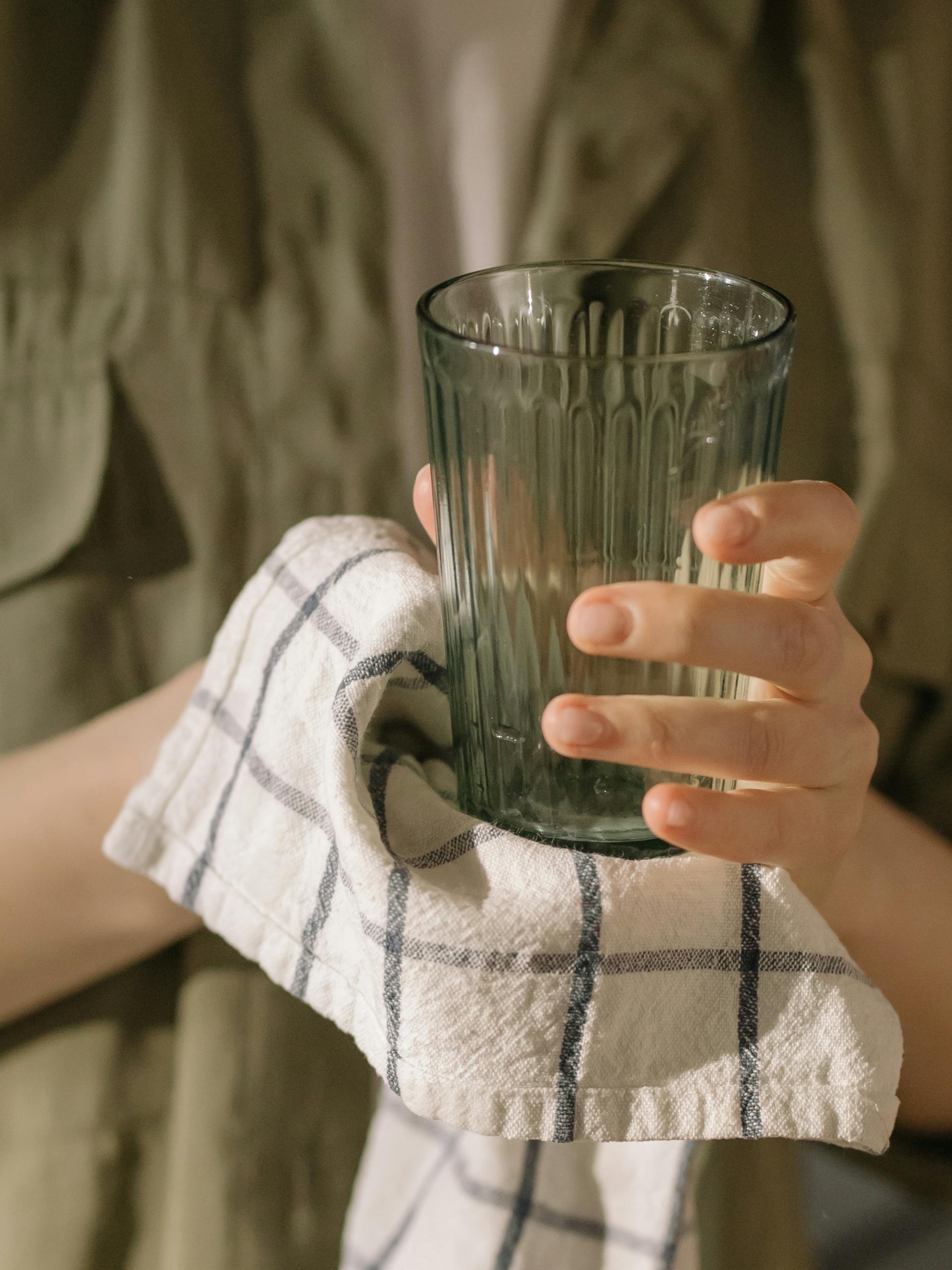 A woman drying a glass with a towel | Source: Pexels