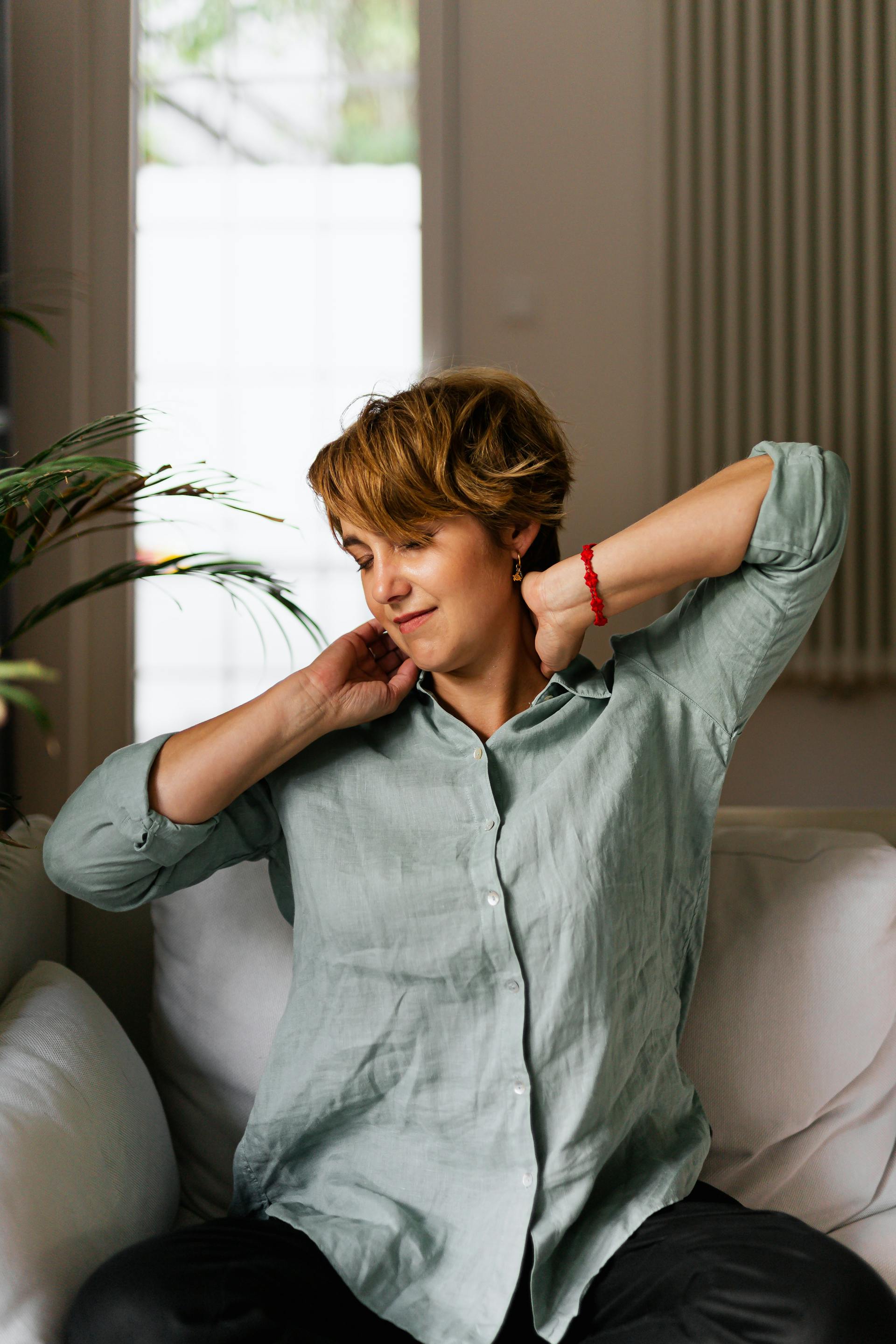 A woman stretching while sitting on a couch | Source: Pexels