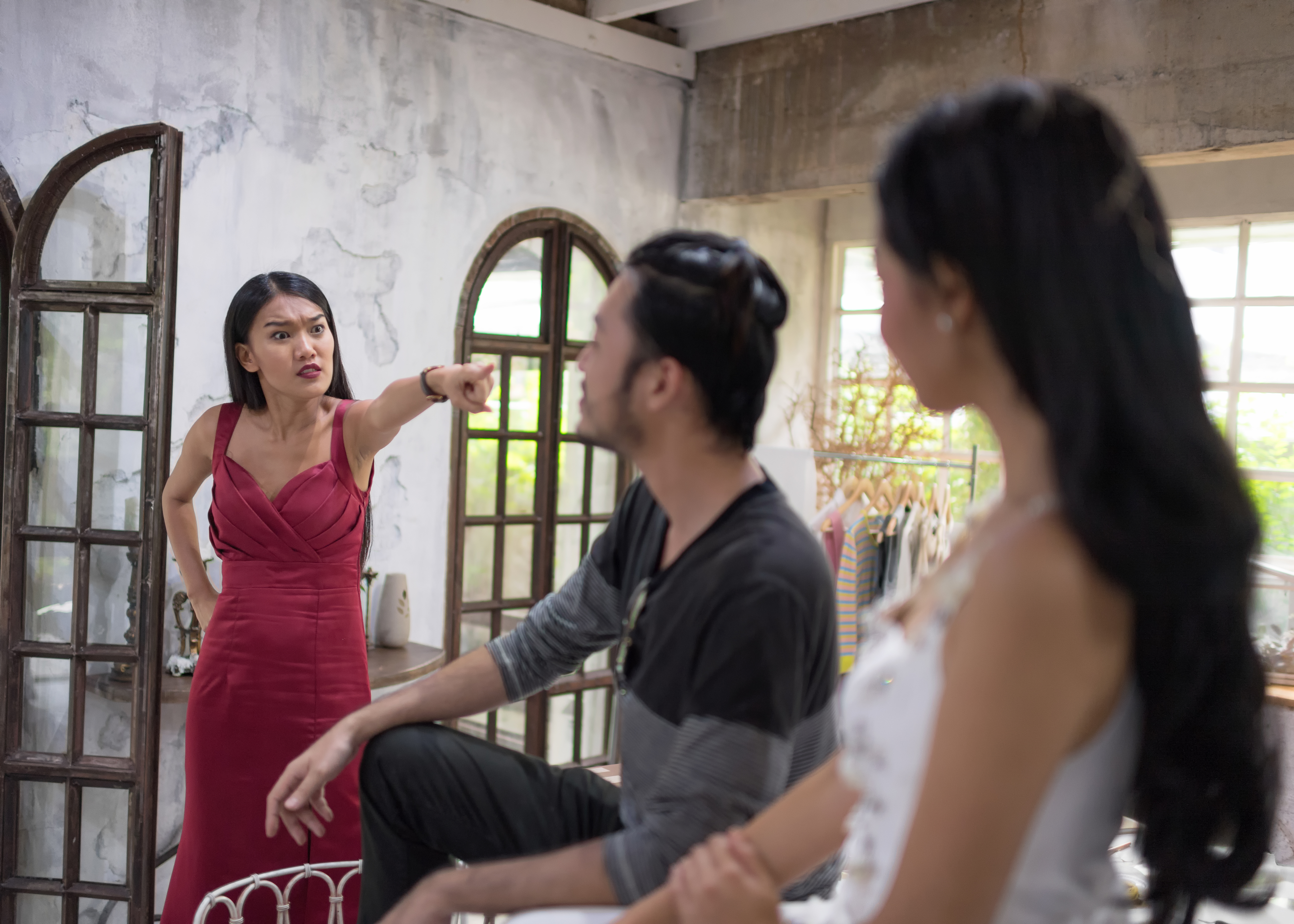 An angry woman looking at a man sitting with another woman | Source: Shutterstock