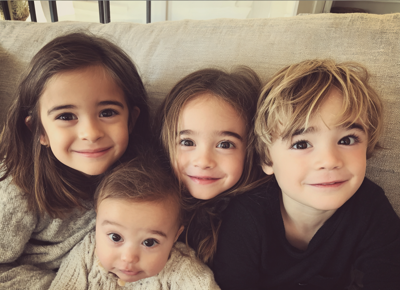 Four young children sitting on a couch | Source: Midjourney