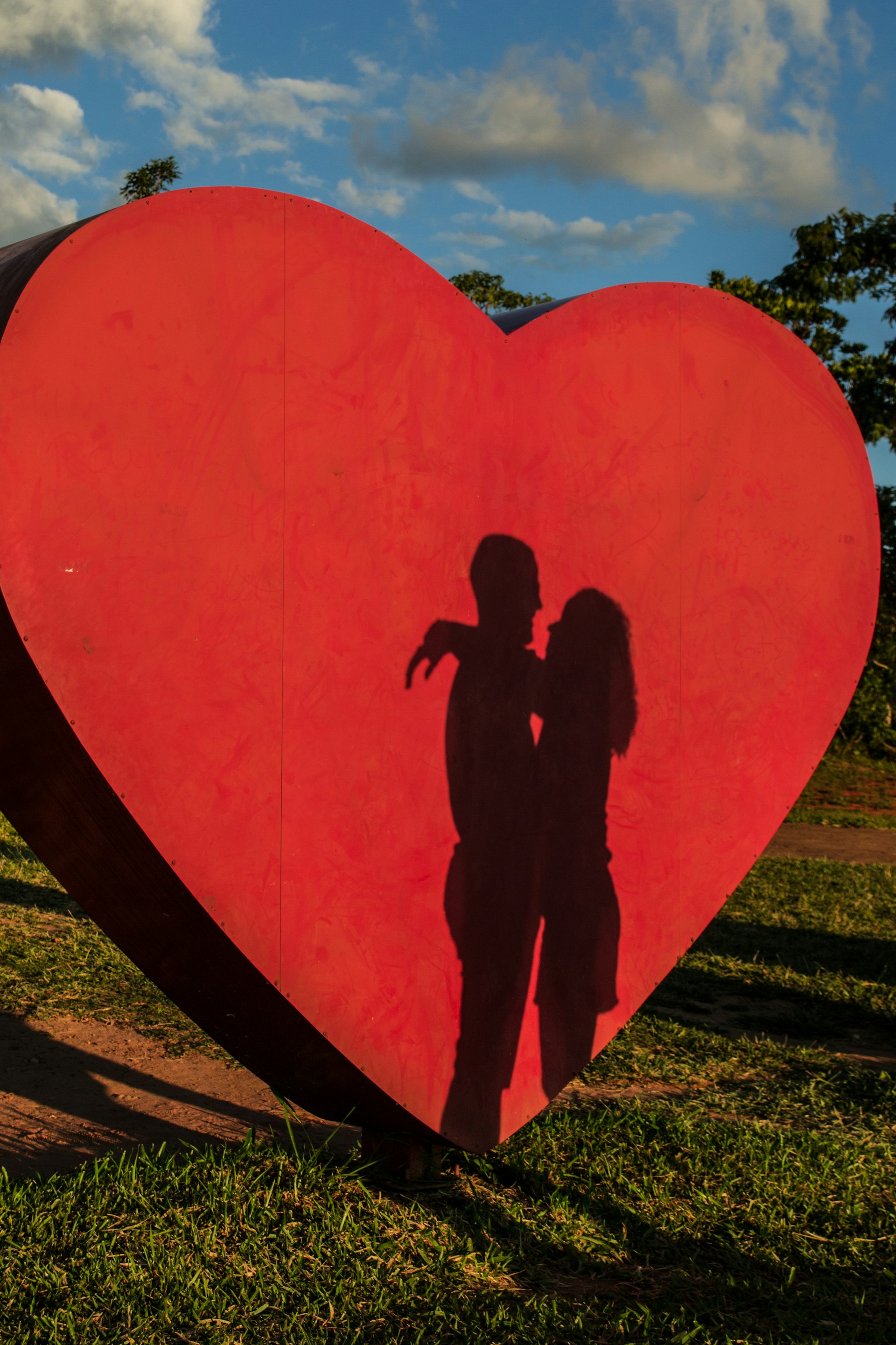 Shadow of a couple hugging each other against the backdrop of a giant heart-shaped cut out | Source: Unsplash