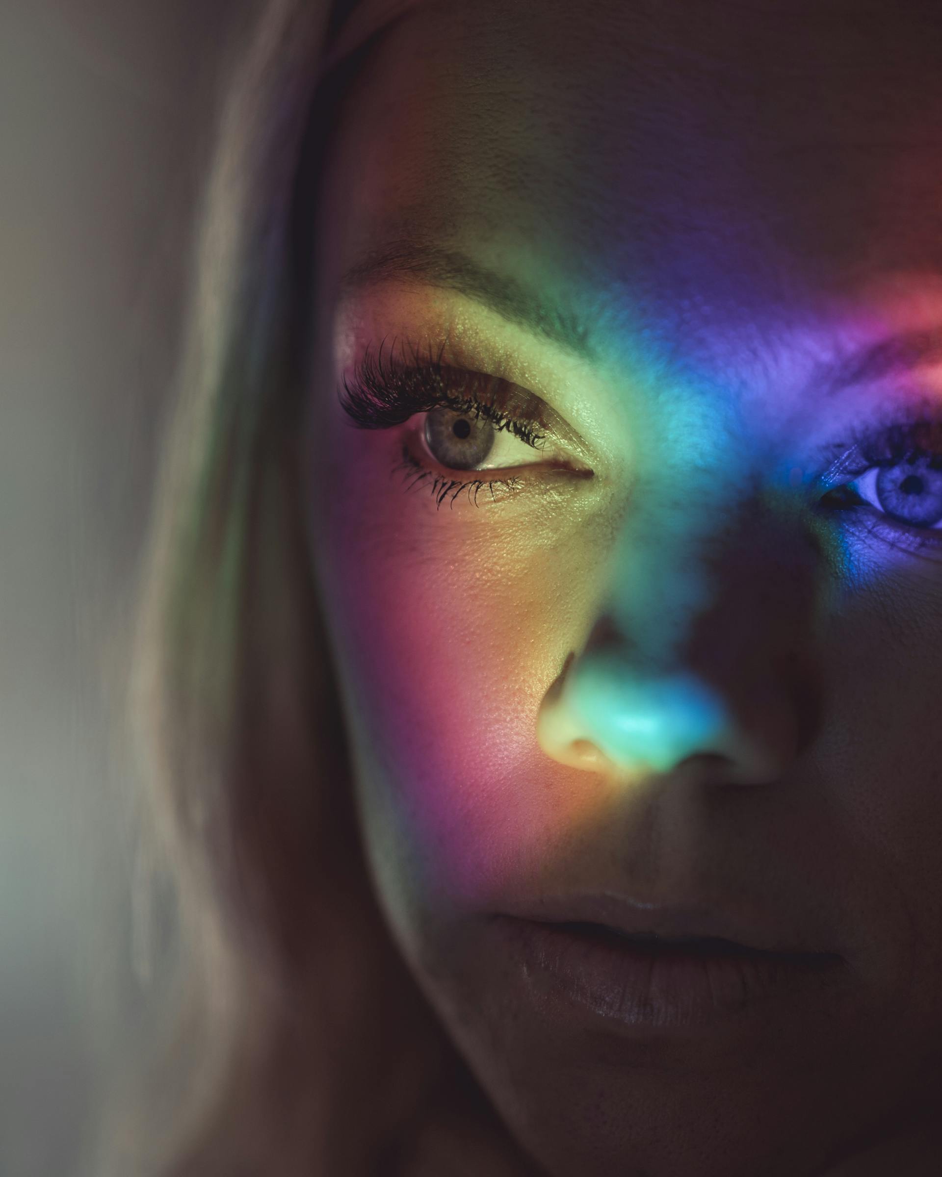 A beautiful woman's face with colorful lights on it | Source: Pexels