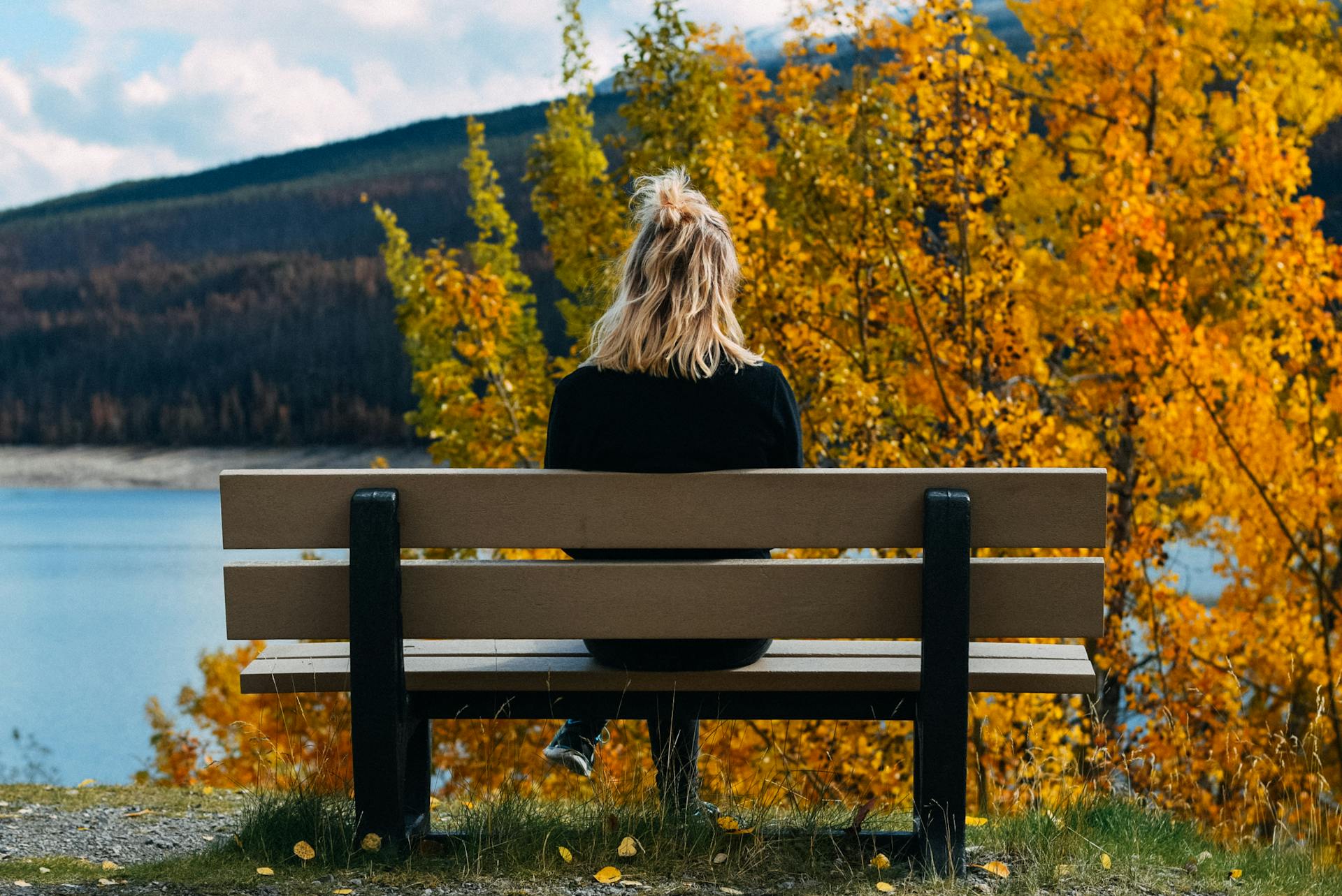 A woman sitting on a bench and looking at the lake | Source: Pexels