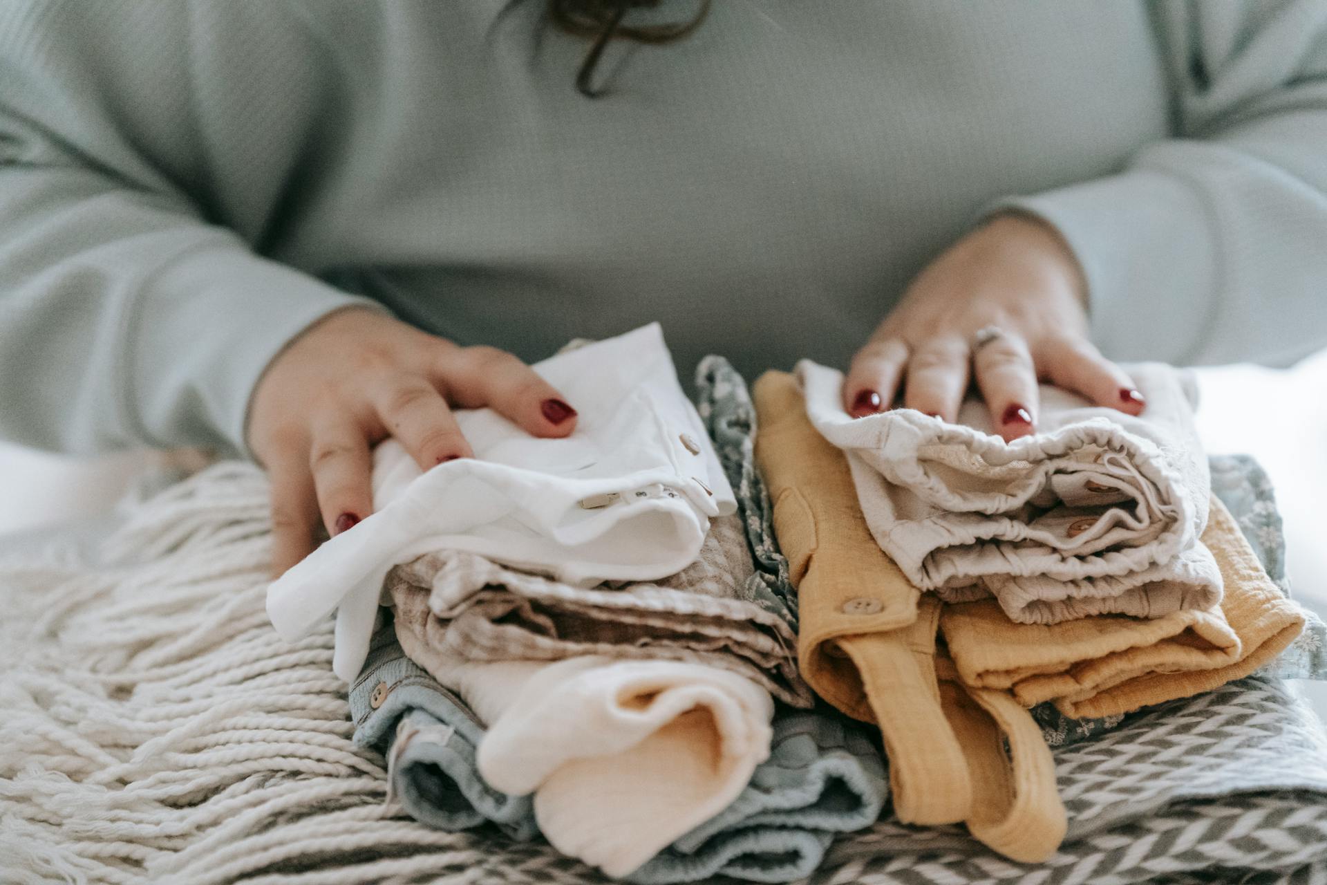 A woman with folded baby clothes | Source: Pexels