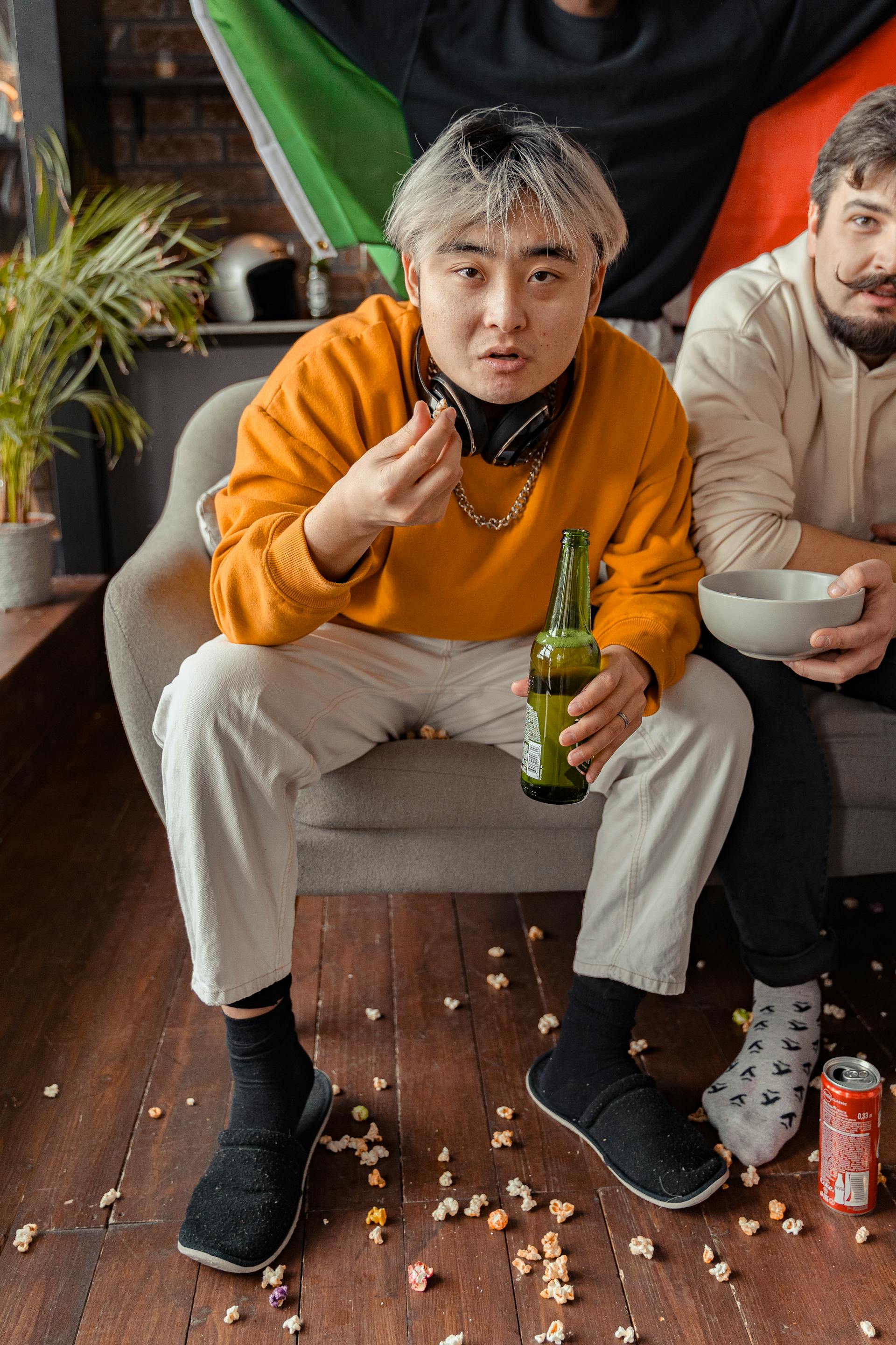 Two men sitting on the couch having beer and popcorns | Source: Pexels
