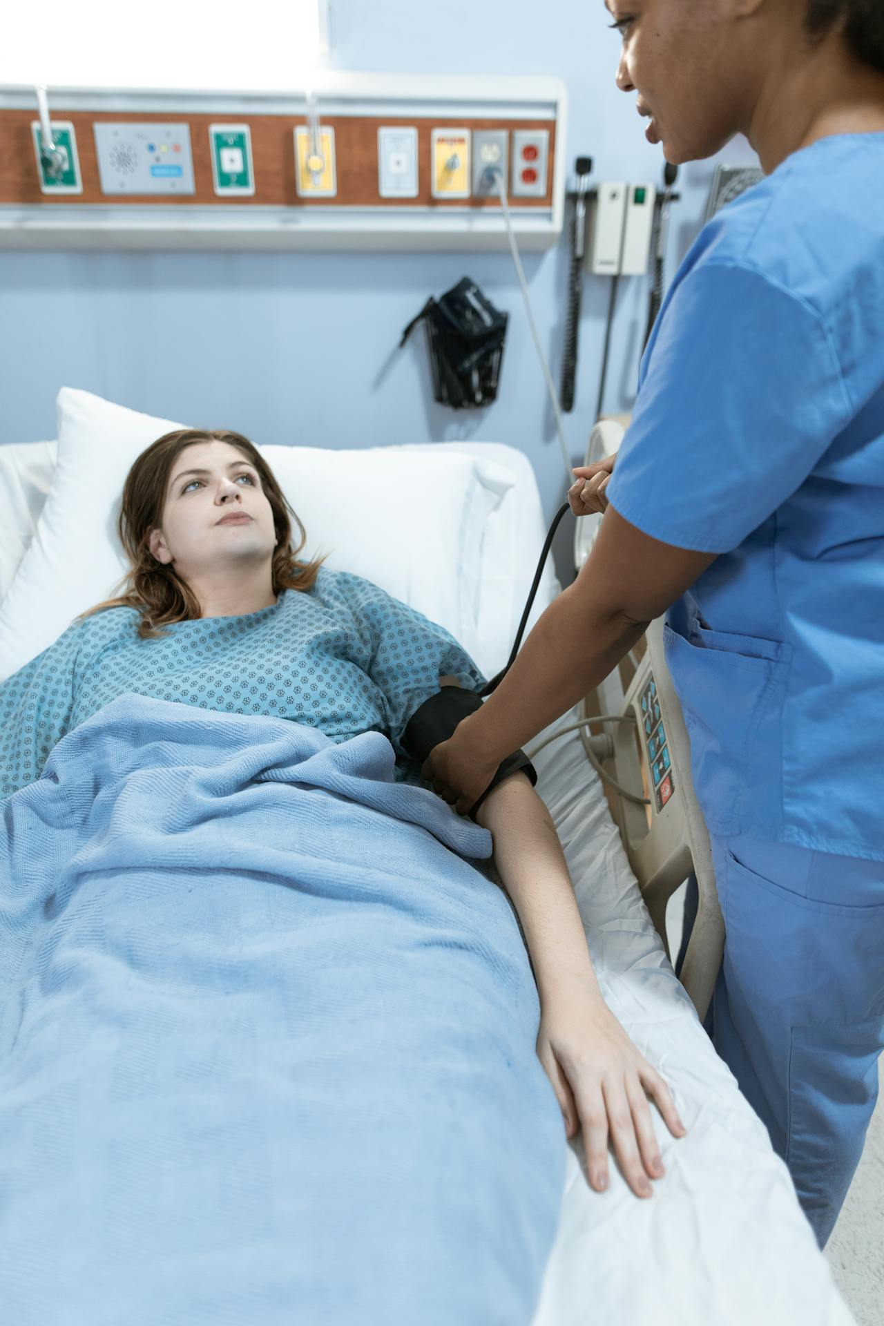 A woman lying in a hospital bed and looking at the nurse | Source: Pexels
