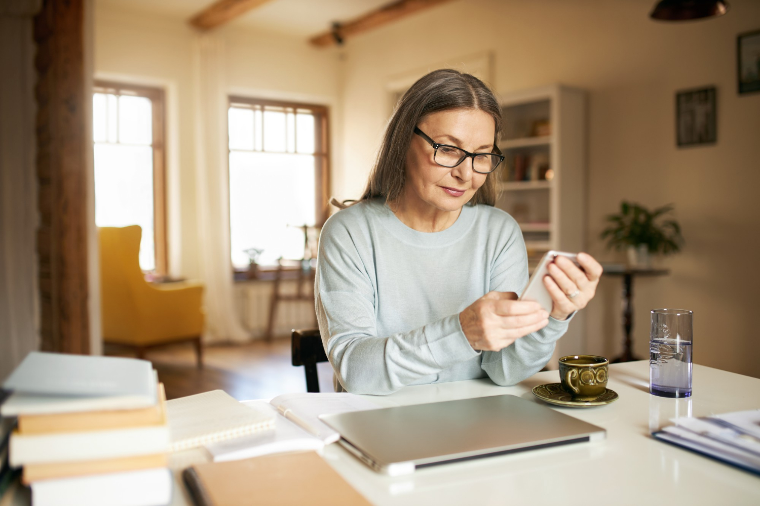 An anxious senior woman holding her phone | Source: Freepik
