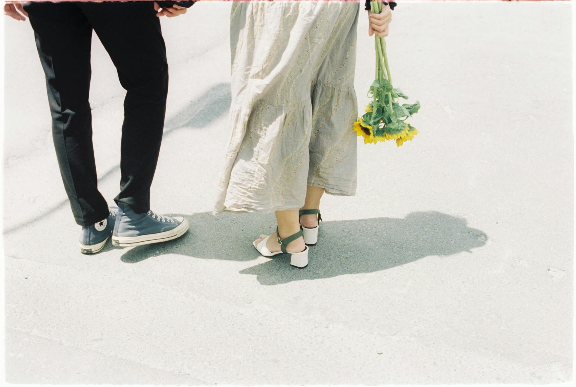 A woman holding a bunch of sunflowers and walking with her partner | Source: Pexels