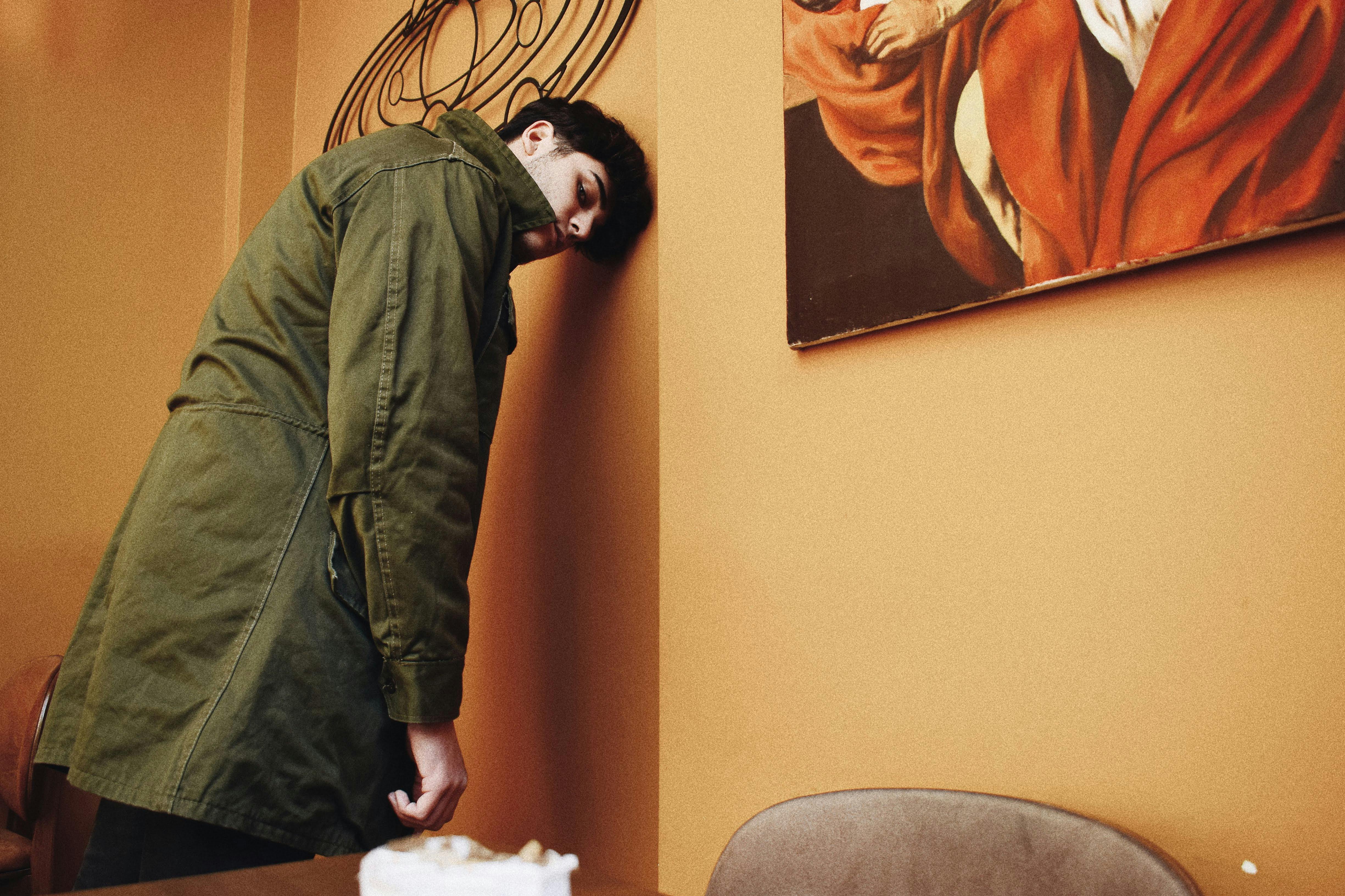 An exhausted man leaning against a wall | Source: Pexels