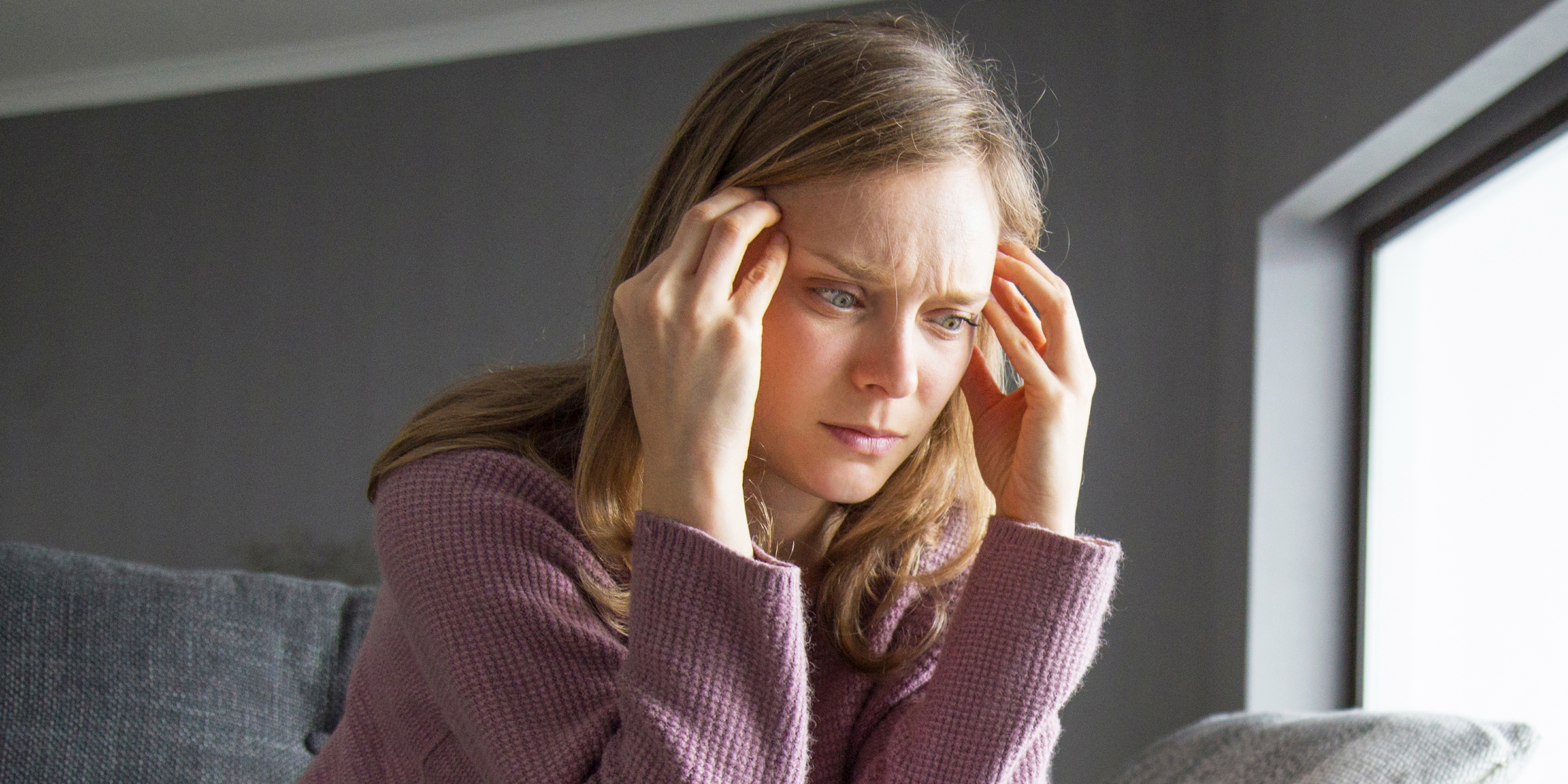 A worried woman pressing her fingers to her temples | Source: Shutterstock