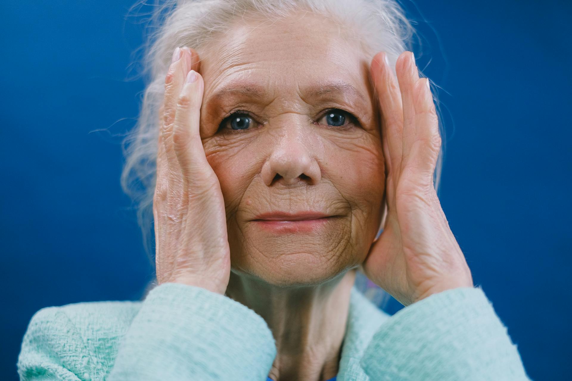 An older woman touching her temples | Source: Pexels