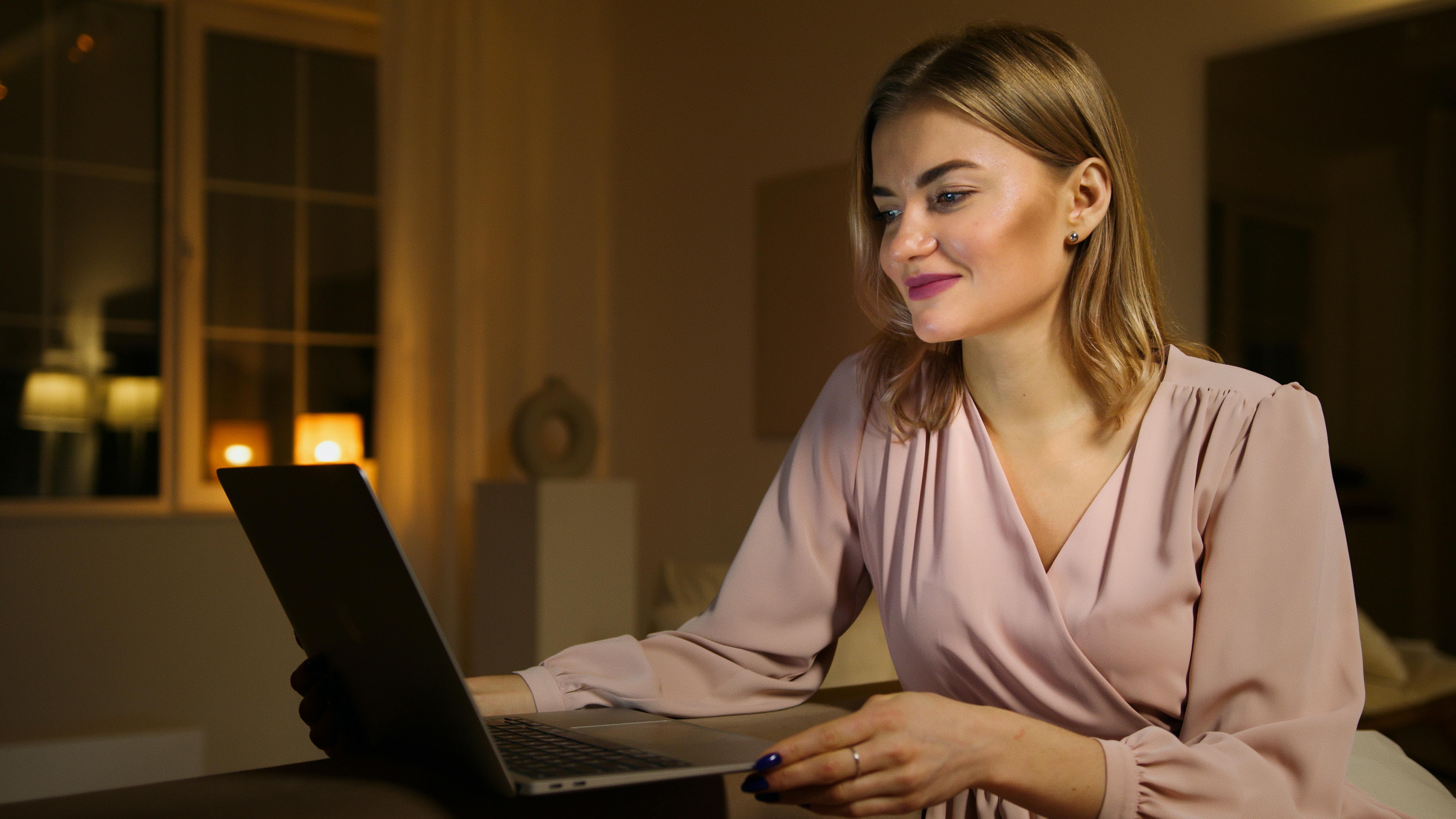 A woman looking at a laptop while smiling | Source: Pexels