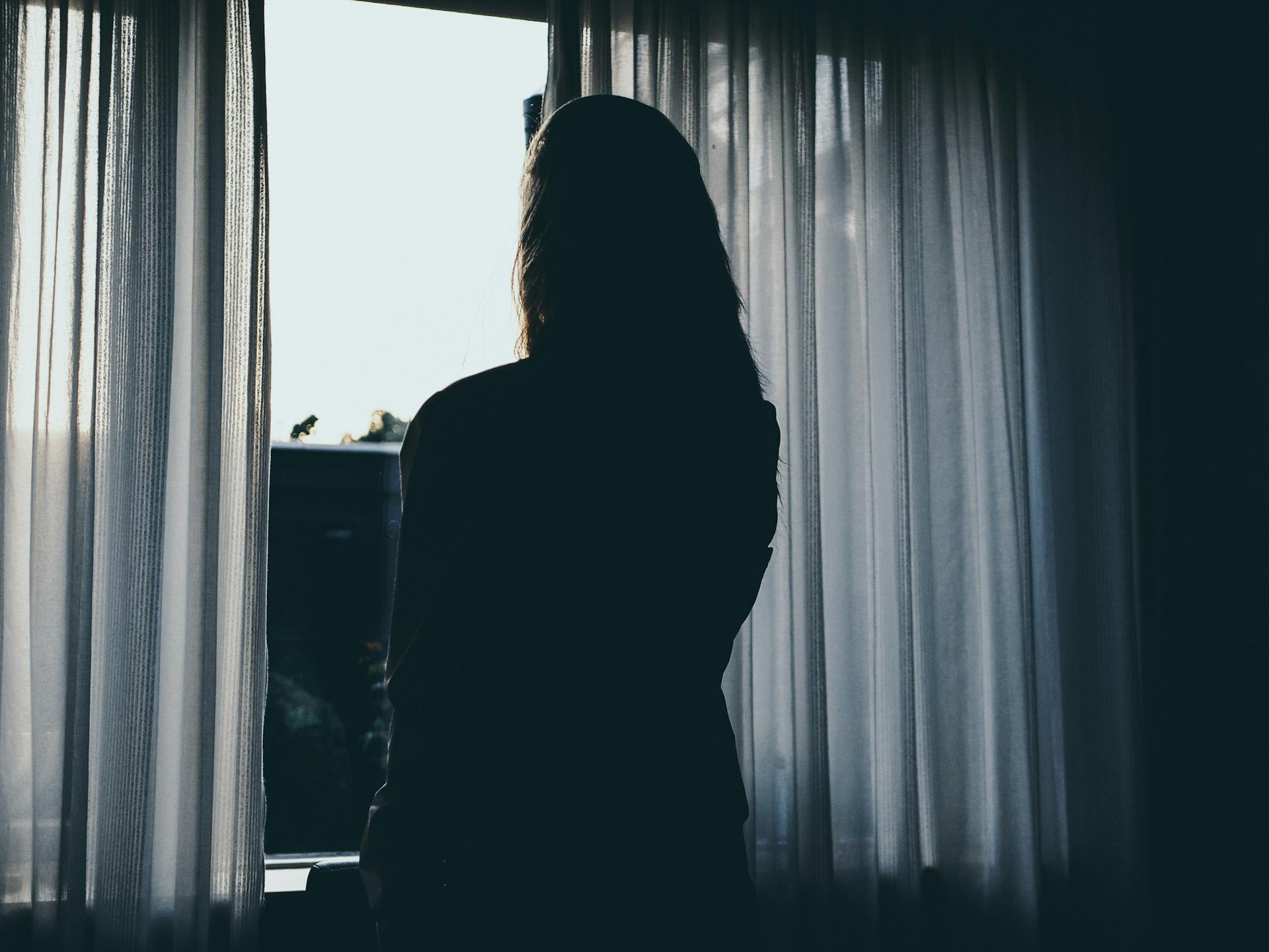 A woman standing near a window | Source: Pexels