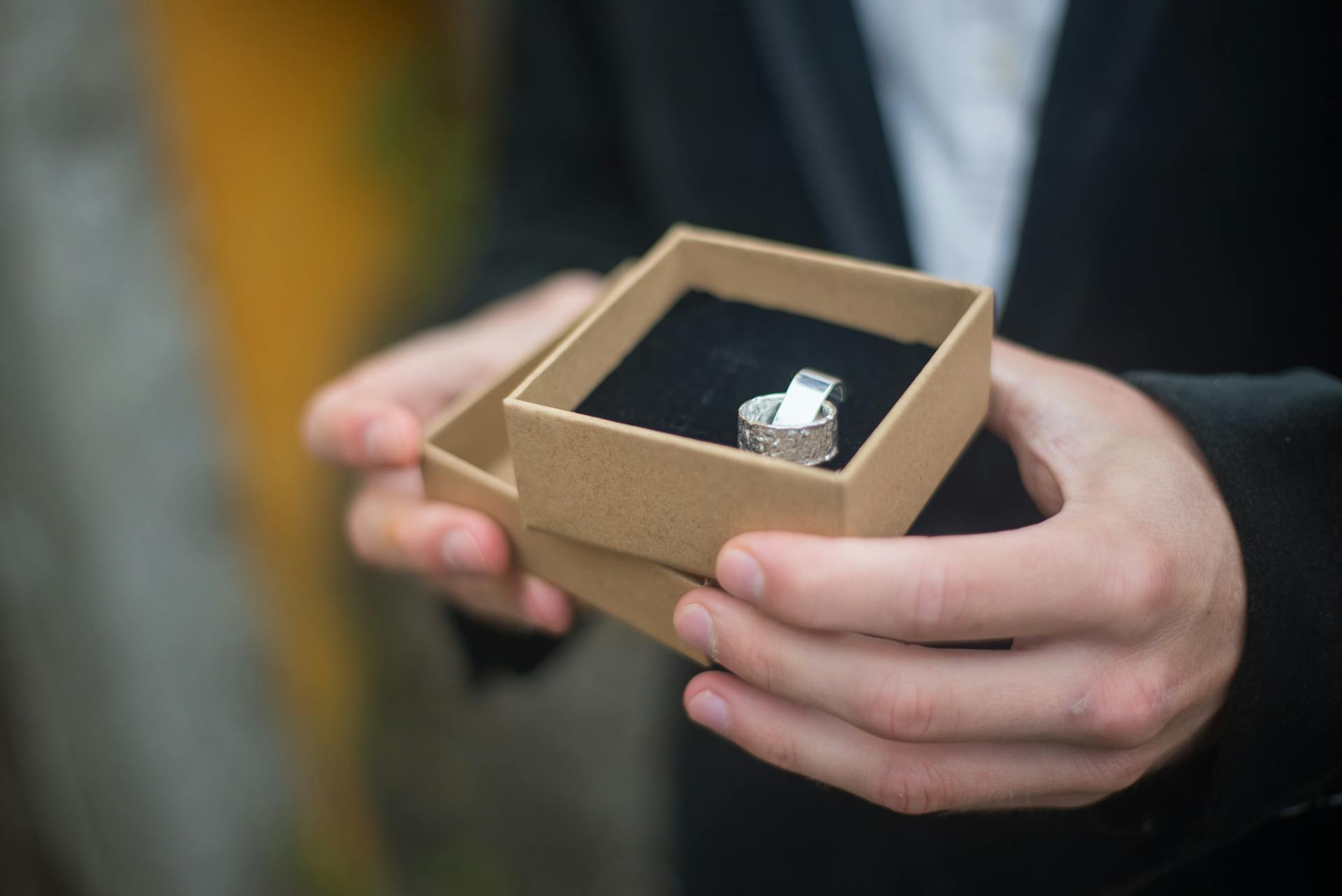 Close-up cropped shot of a man holding a brown box with a ring | Source: Pexels