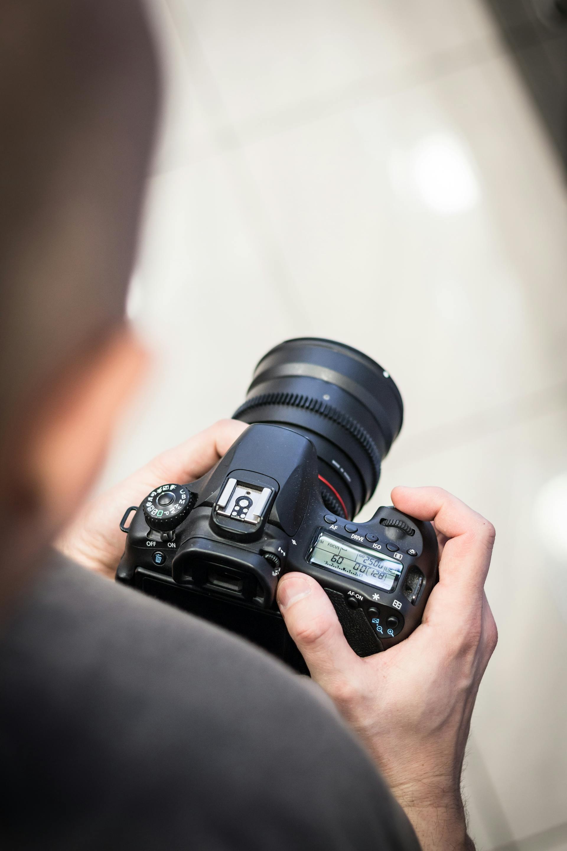 A man holding a DSLR camera | Source: Pexels