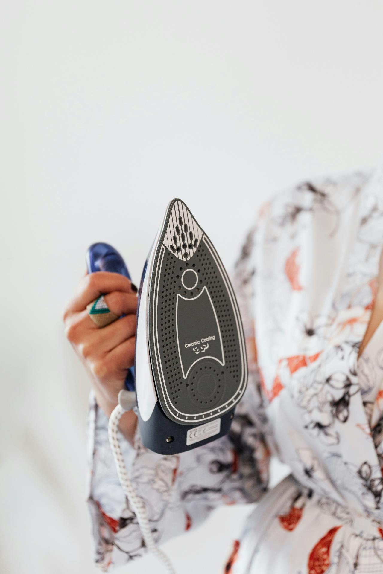 A woman holding a steam iron | Source: Pexels
