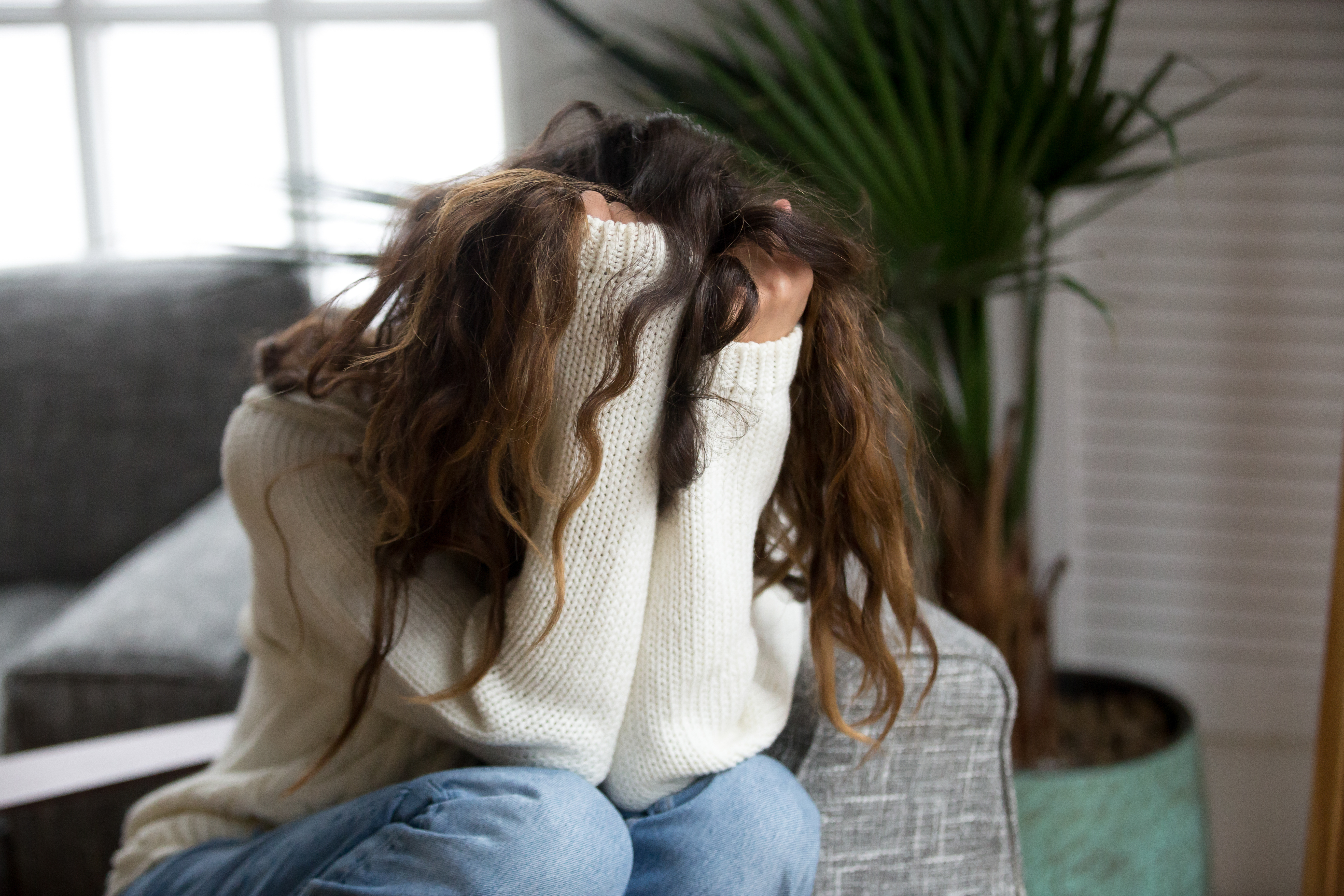 A depressed woman hiding her face with her hands | Source: Shutterstock