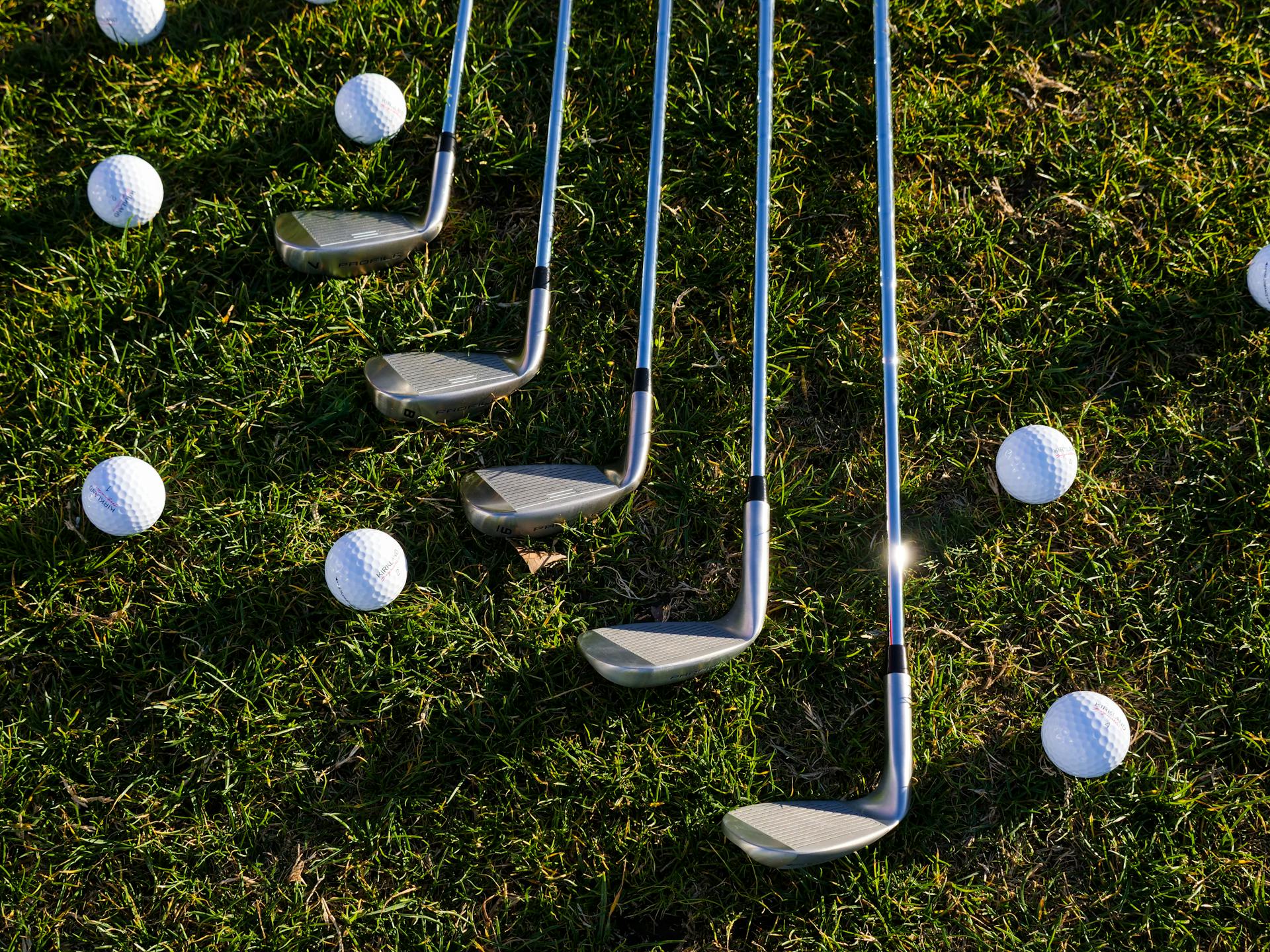 Golf balls and golf clubs lying on the grass | Source: Pexels