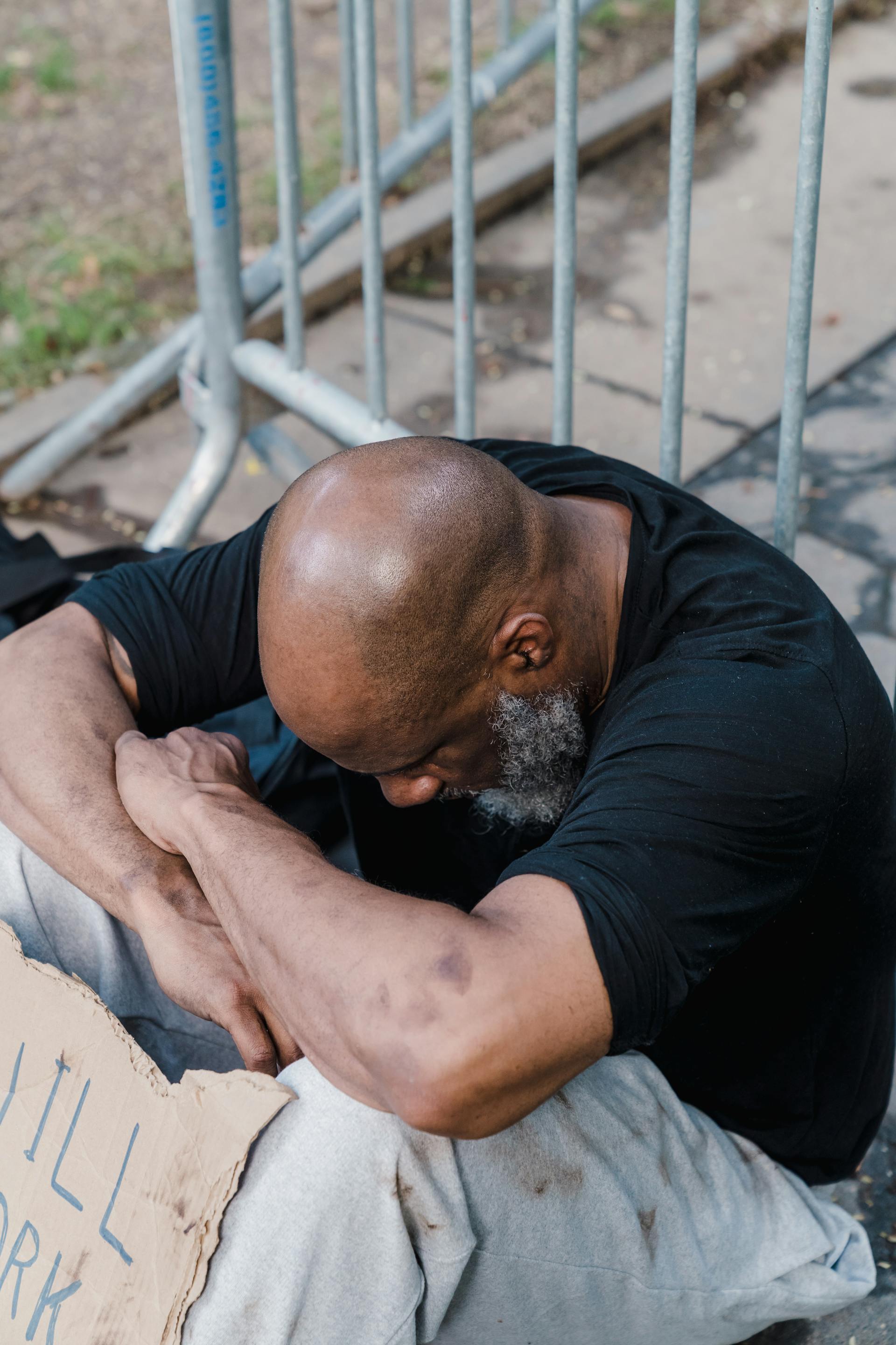 A homeless man sitting with his head bowed down | Source: Pexels