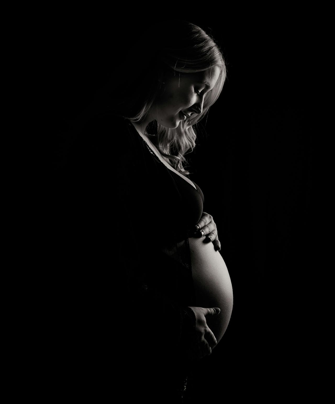 A joyful pregnant woman looking down at her baby bump | Source: Pexels