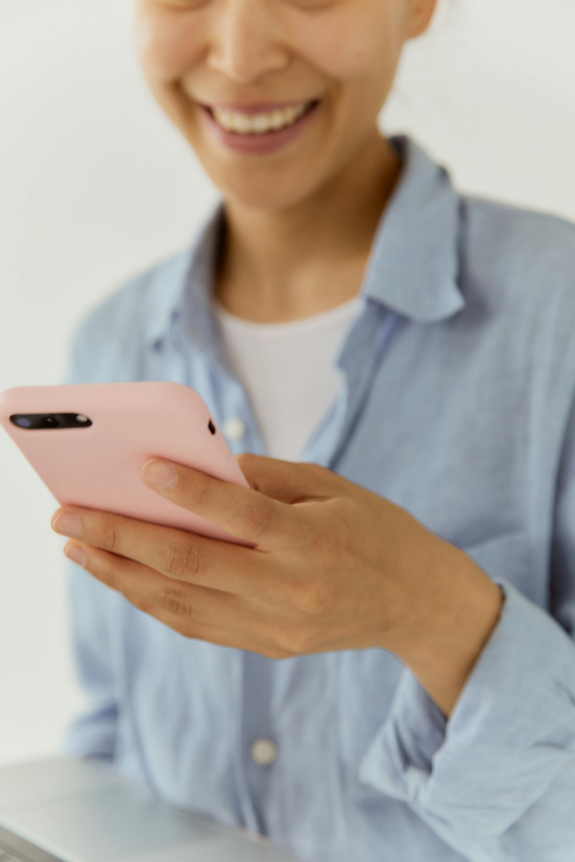 A woman smiling while looking at her phone | Source: Pexels