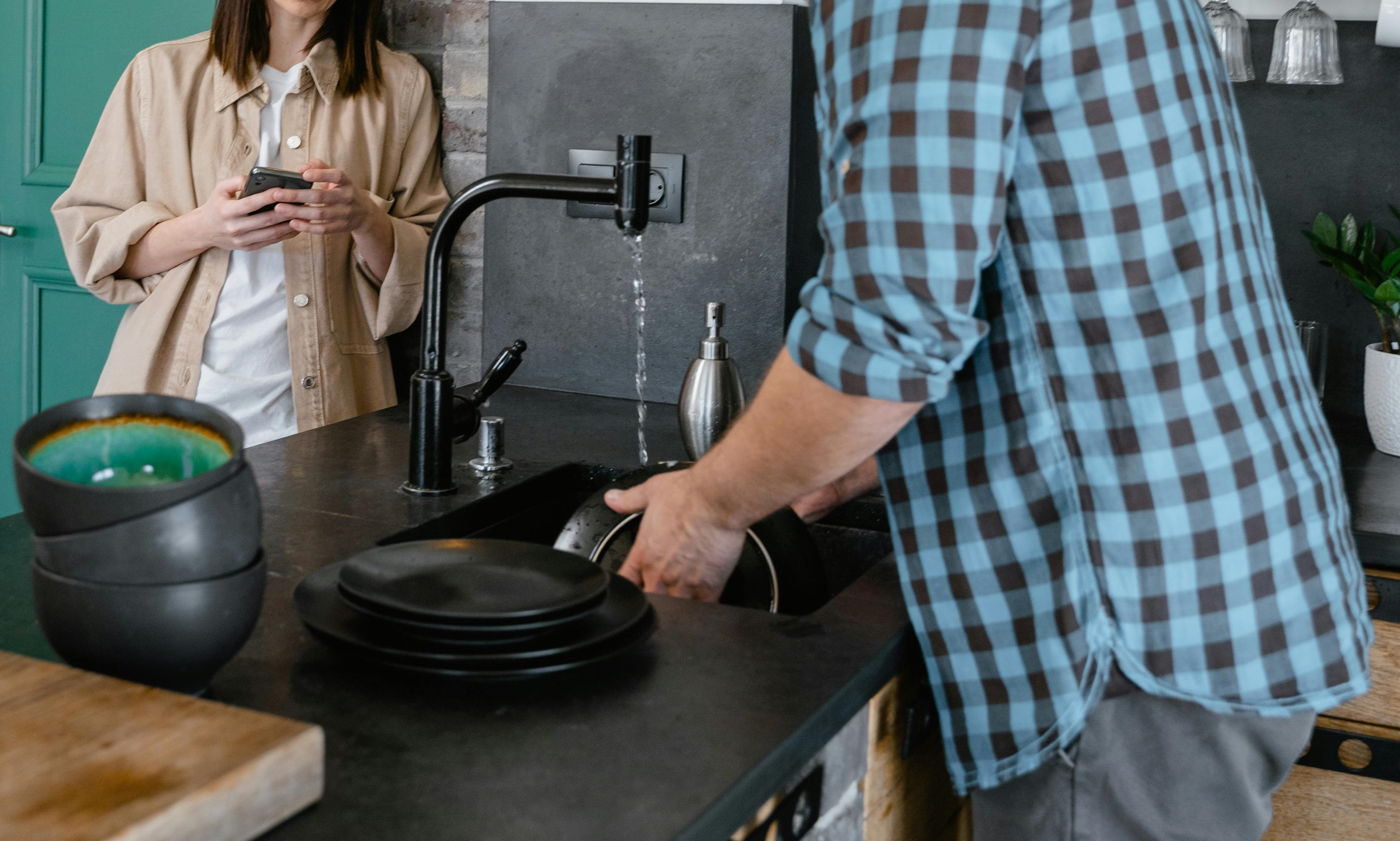 A woman watching a man washing dishes | Source: Pexels